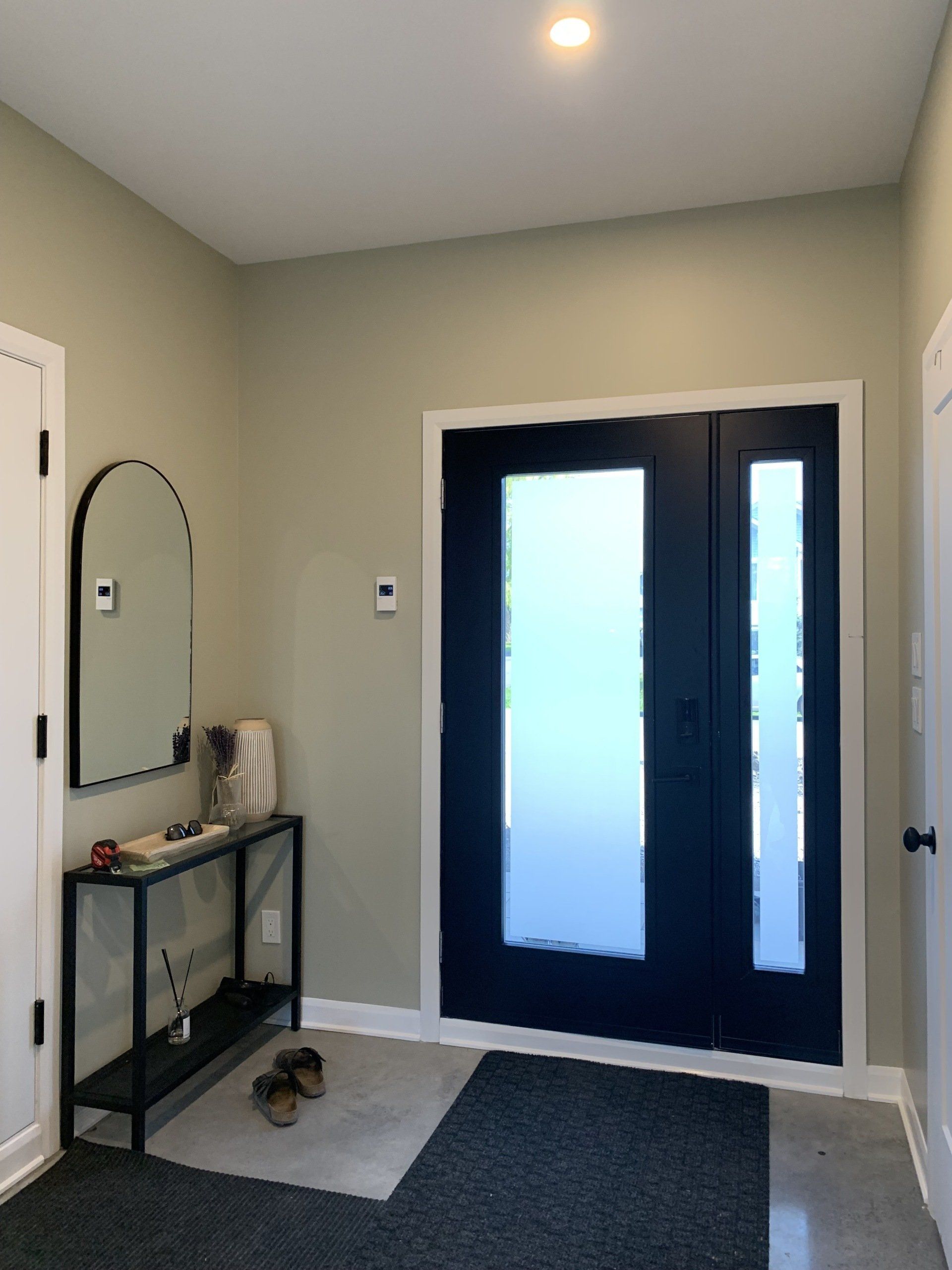 Un couloir avec une porte noire et un miroir