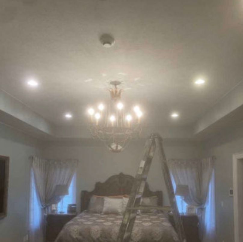 A bedroom with a bed and a chandelier hanging from the ceiling.