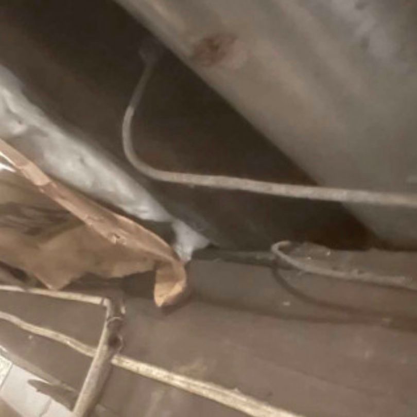 A close up of a pipe and wires in a room.