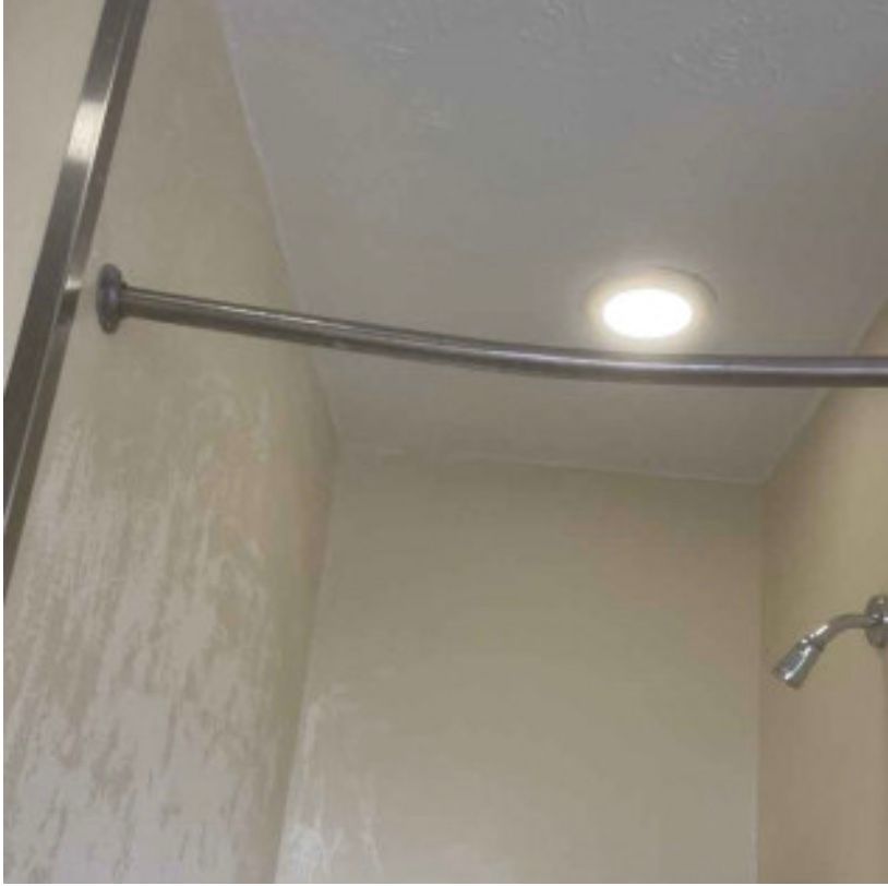 A bathroom with a shower head and a ceiling light