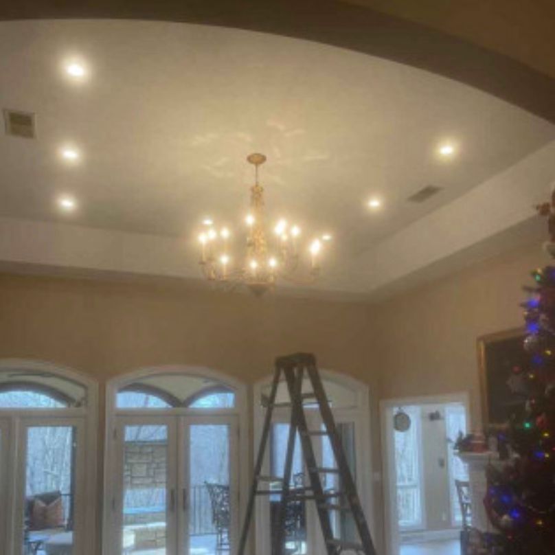A living room with a ladder and a chandelier hanging from the ceiling.