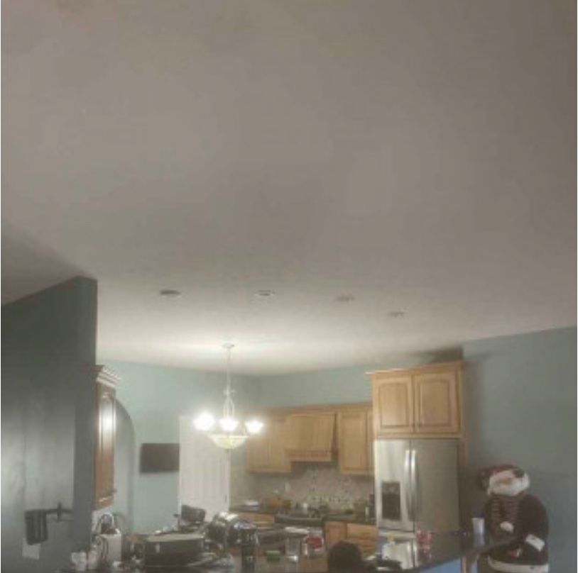 A kitchen with a refrigerator , sink , cabinets , and a chandelier.