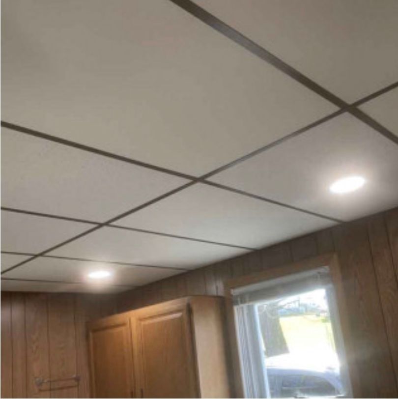 A kitchen with a tiled ceiling and wooden cabinets.