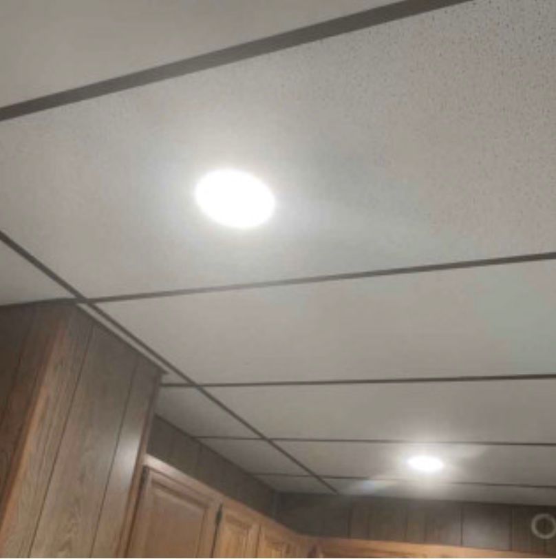 A kitchen with a tiled ceiling and a light on the ceiling.