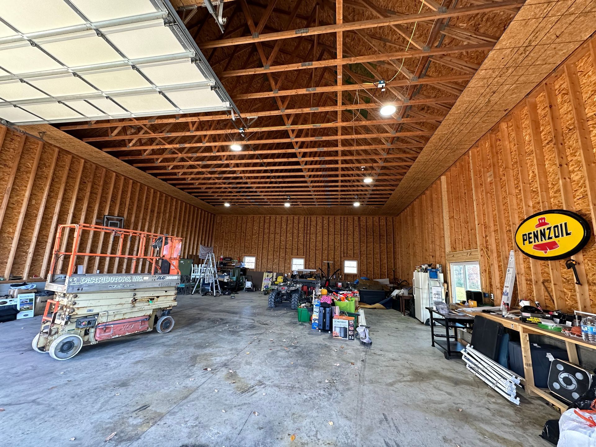 A large wooden garage filled with lots of tools and vehicles.