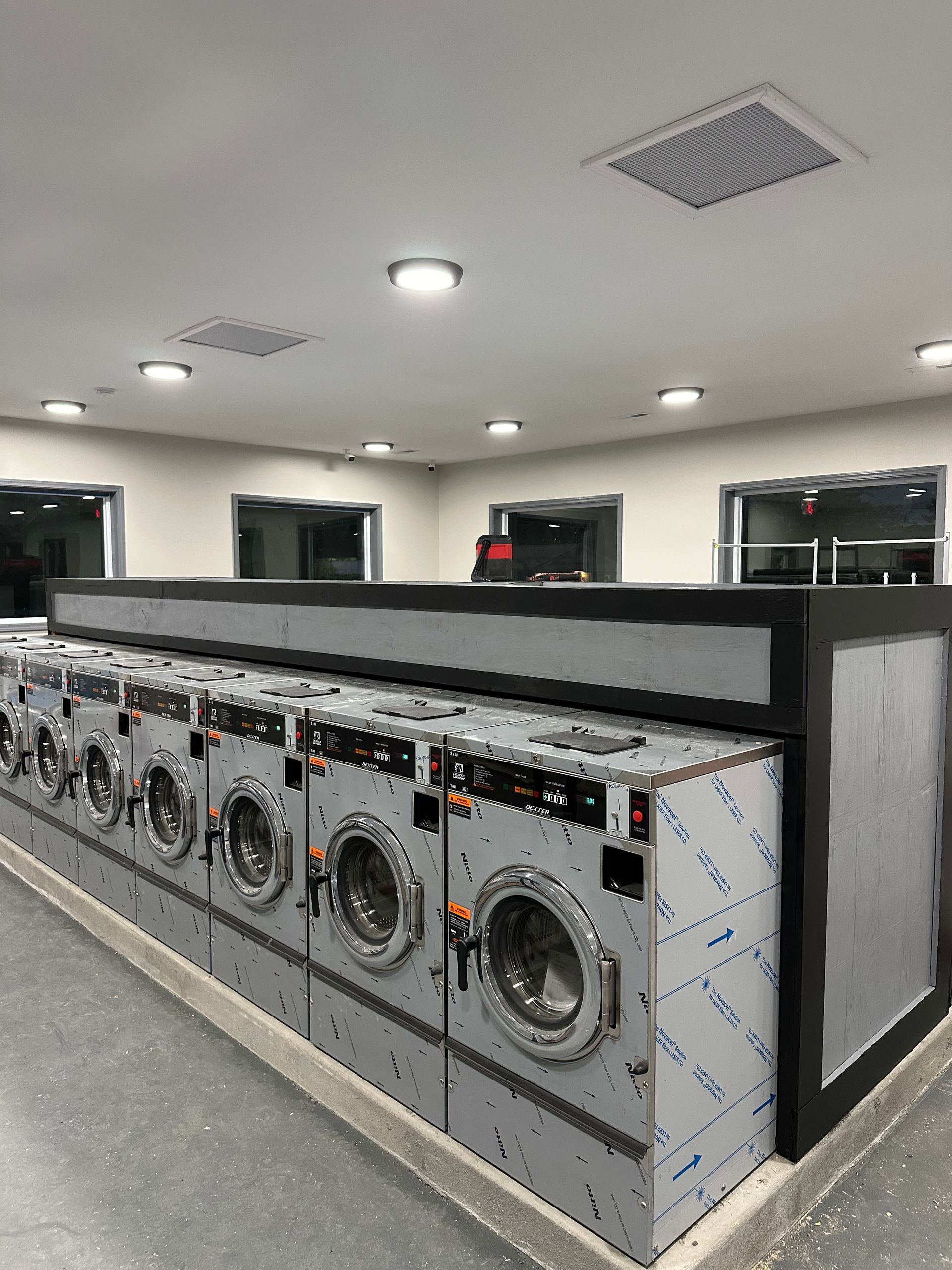 A row of washing machines are lined up in a laundromat.