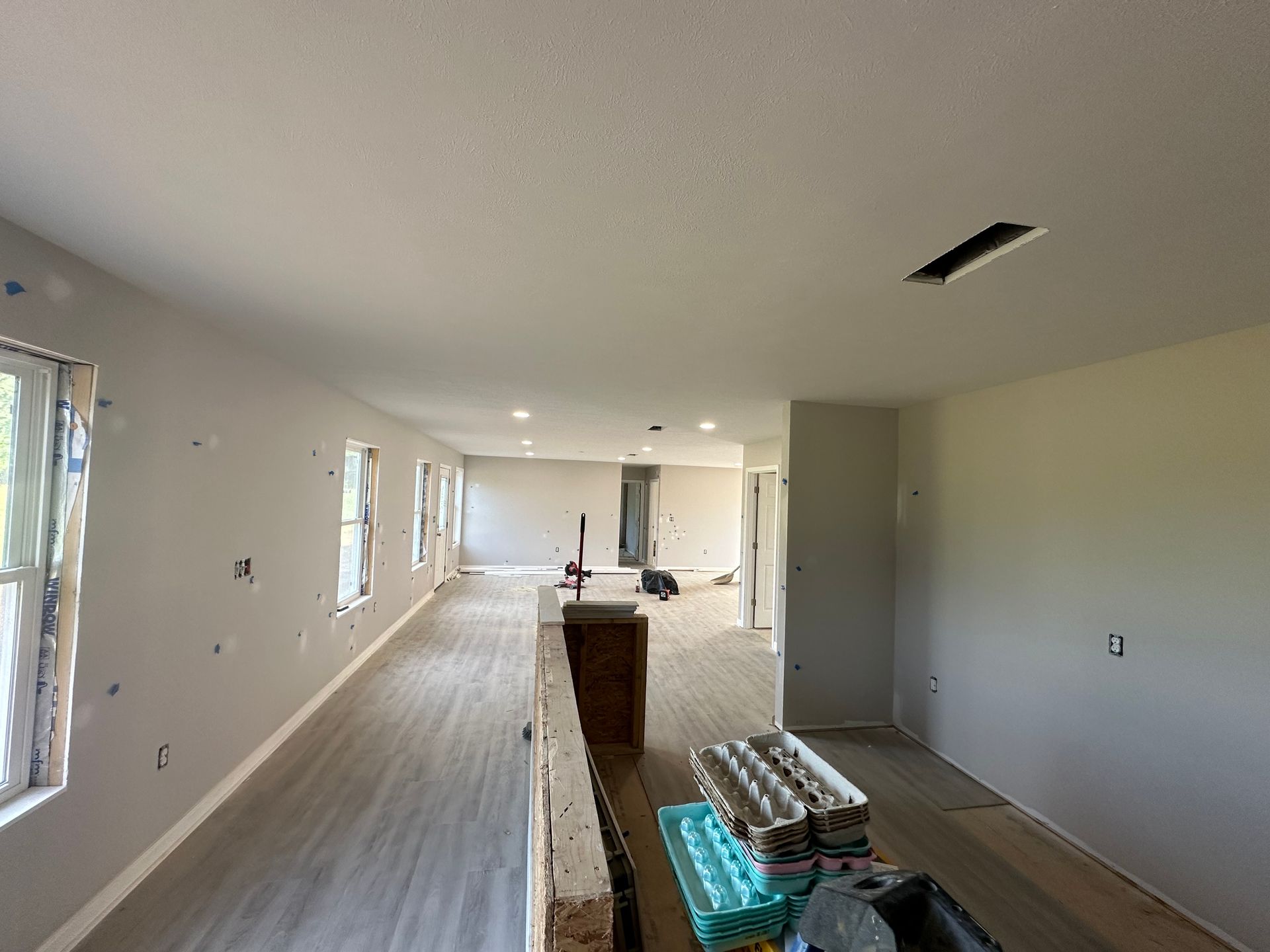 A large room with hardwood floors and white walls is being remodeled.