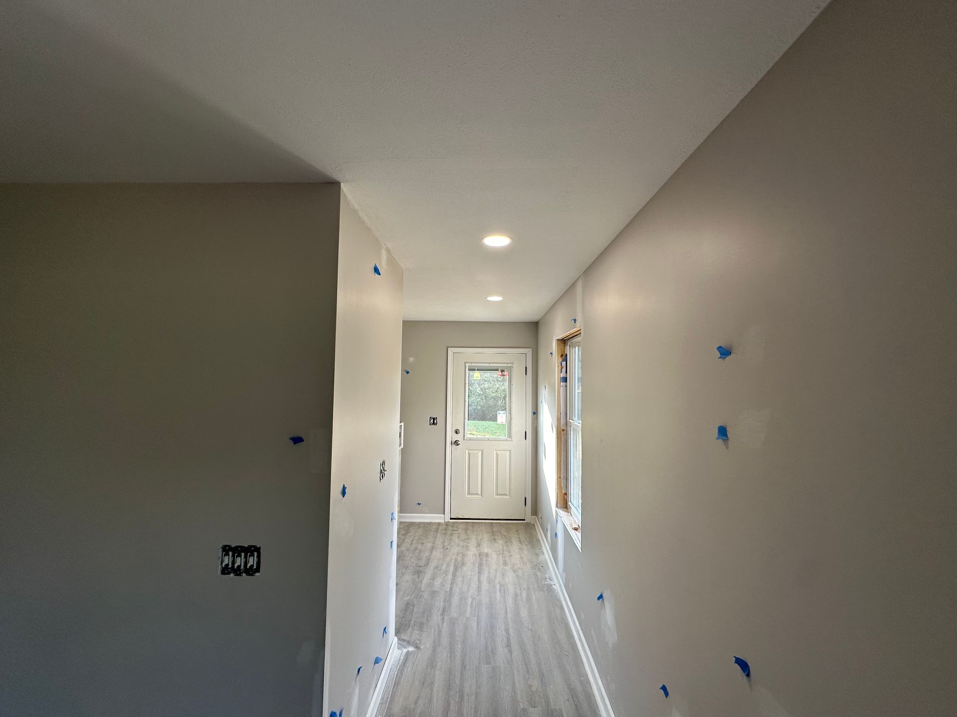 A hallway with a door and a window in a house under construction.