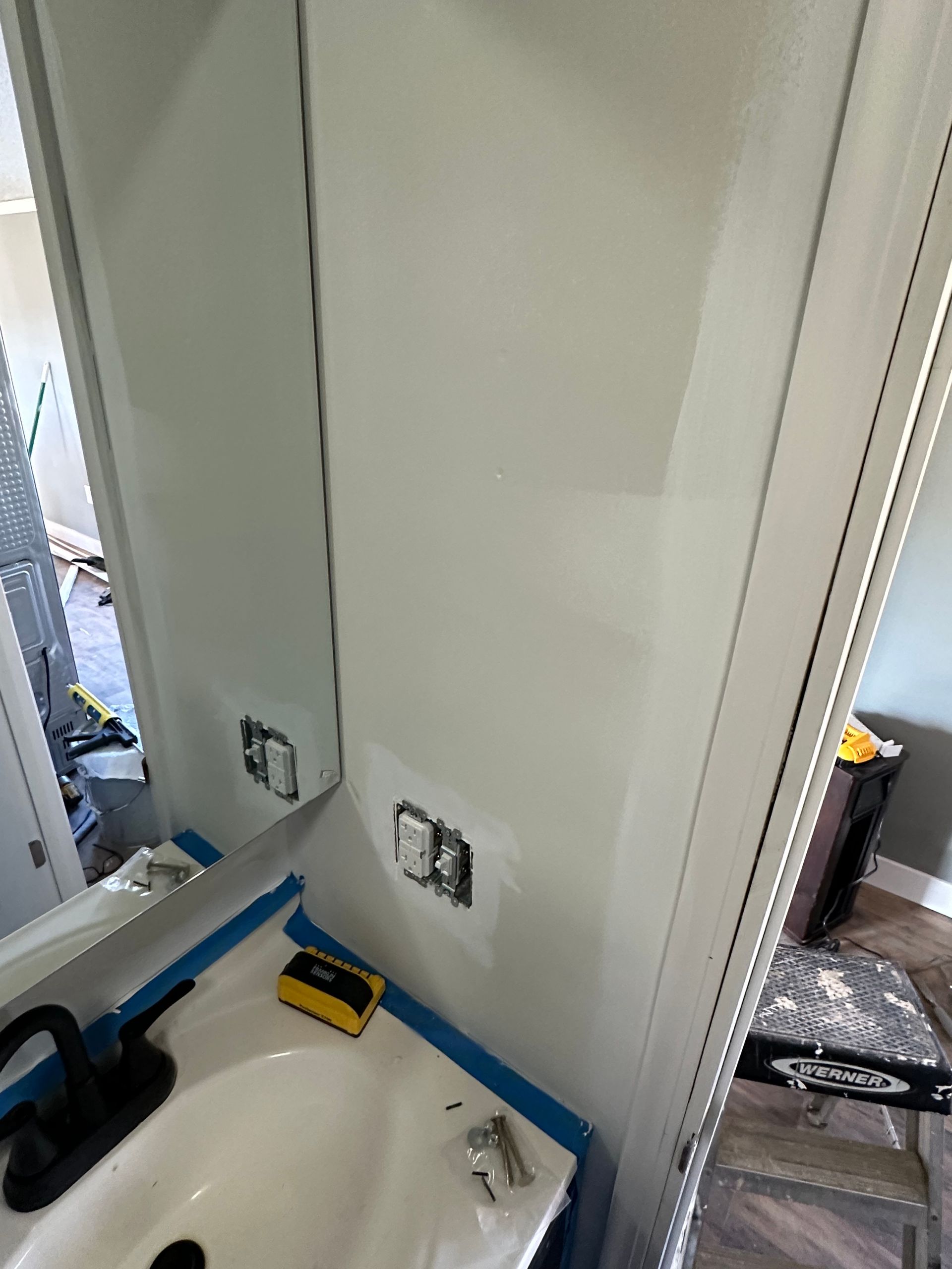 A bathroom with a sink , mirror and light switches.