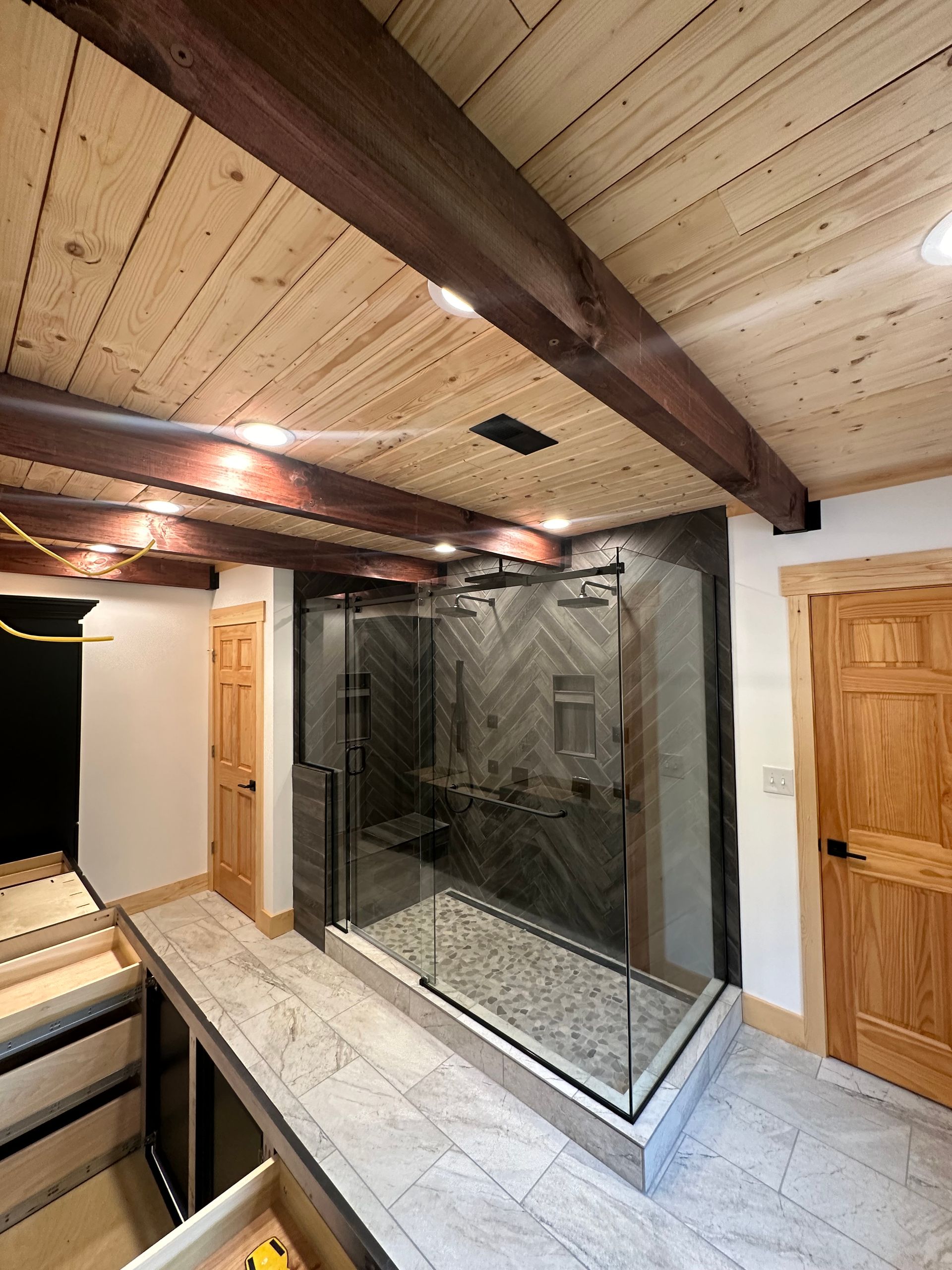 A bathroom with a walk in shower and a wooden ceiling.