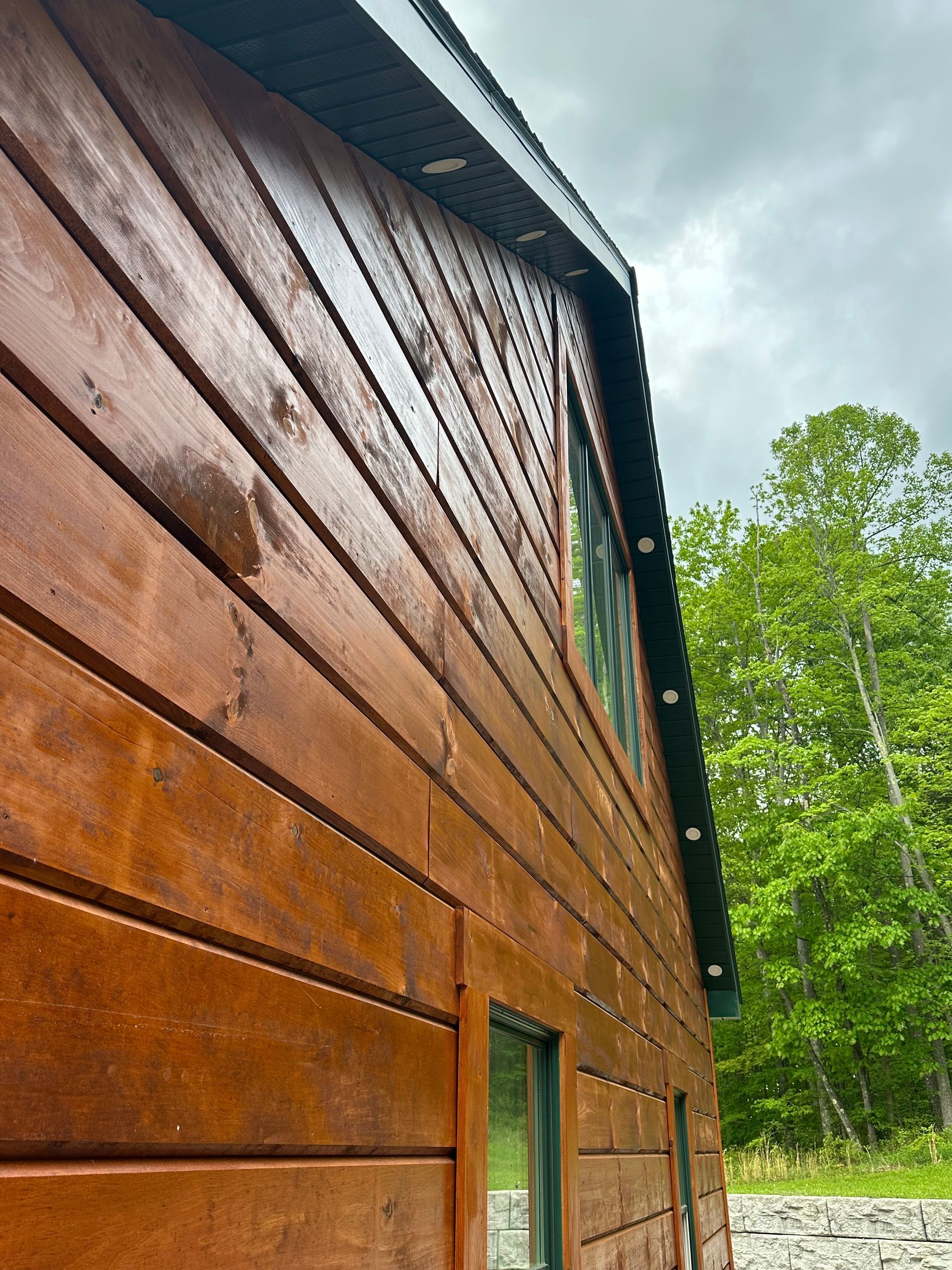 A close up of a wooden house with trees in the background.
