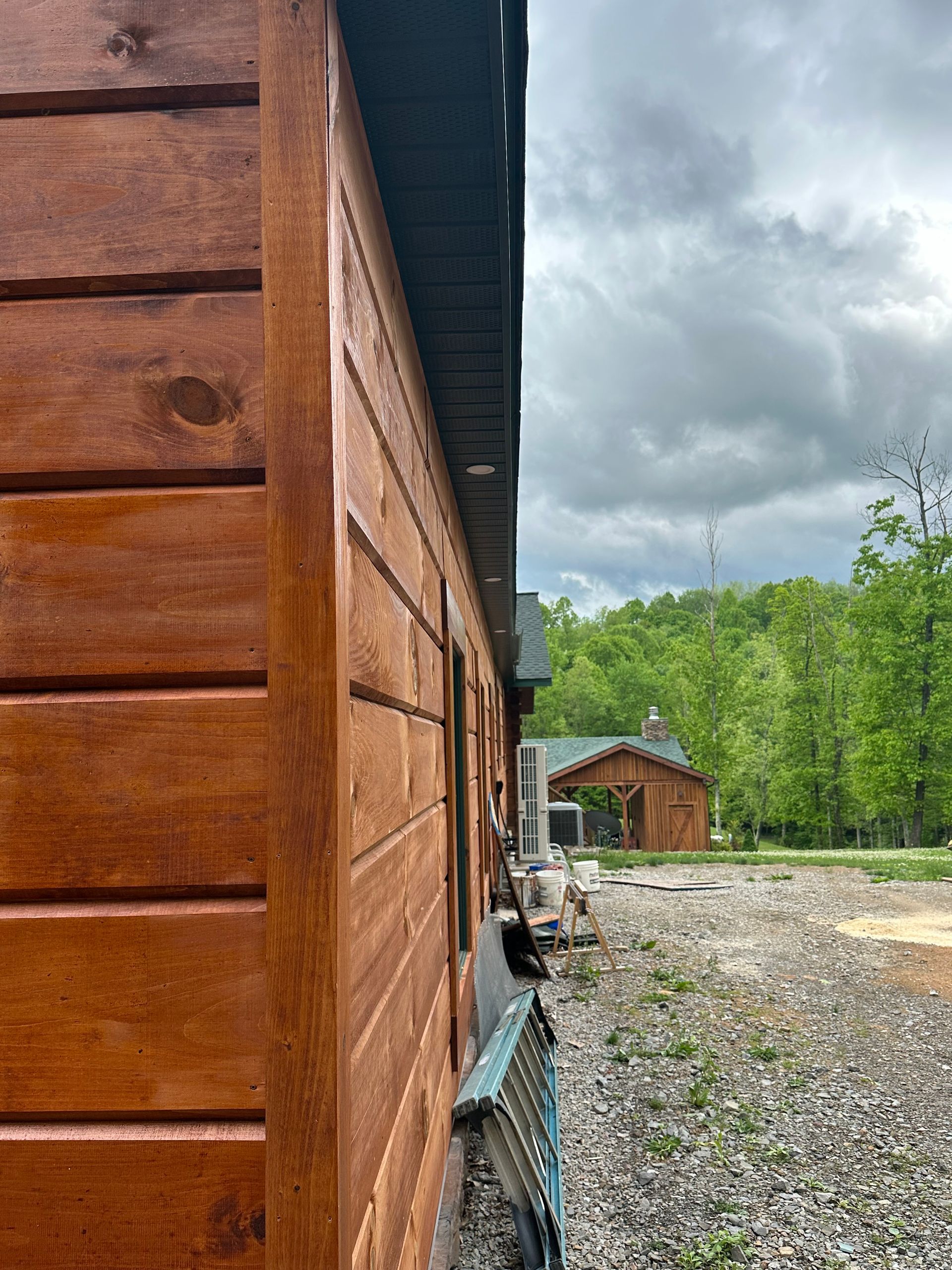 A wooden house is sitting in the middle of a dirt field.