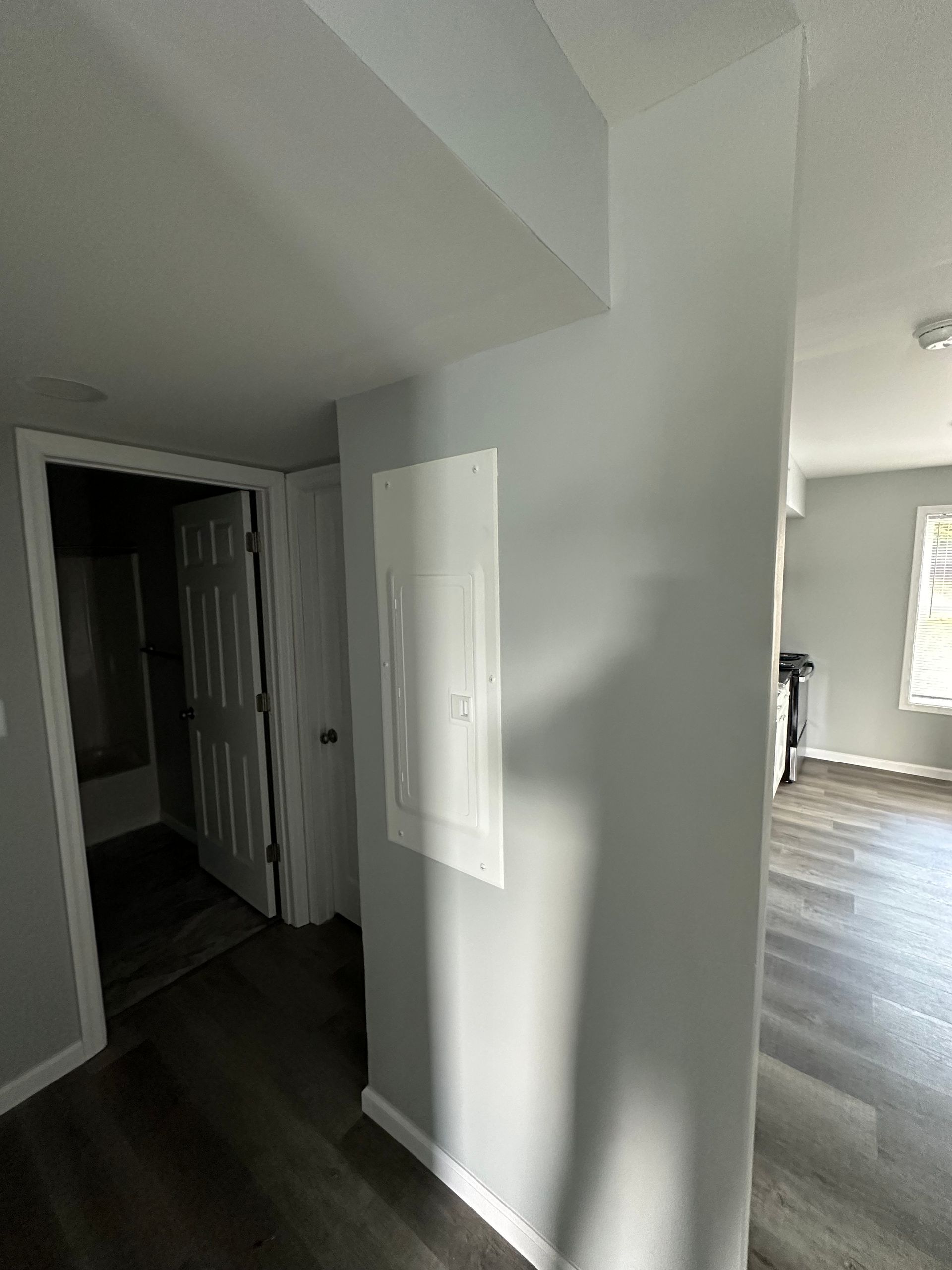 A hallway in a house with a light switch on the wall.