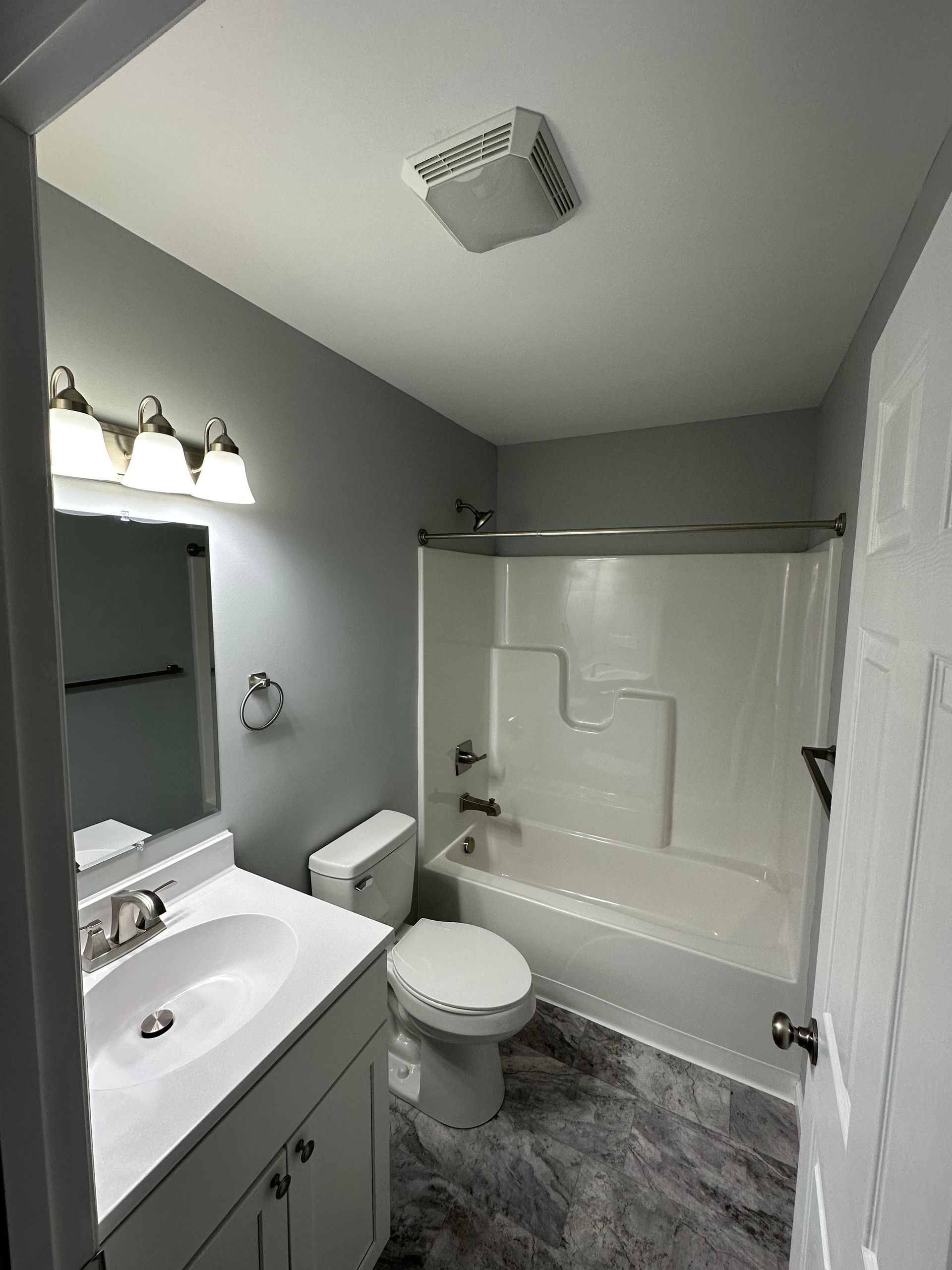 A bathroom with a toilet , sink , bathtub and mirror.