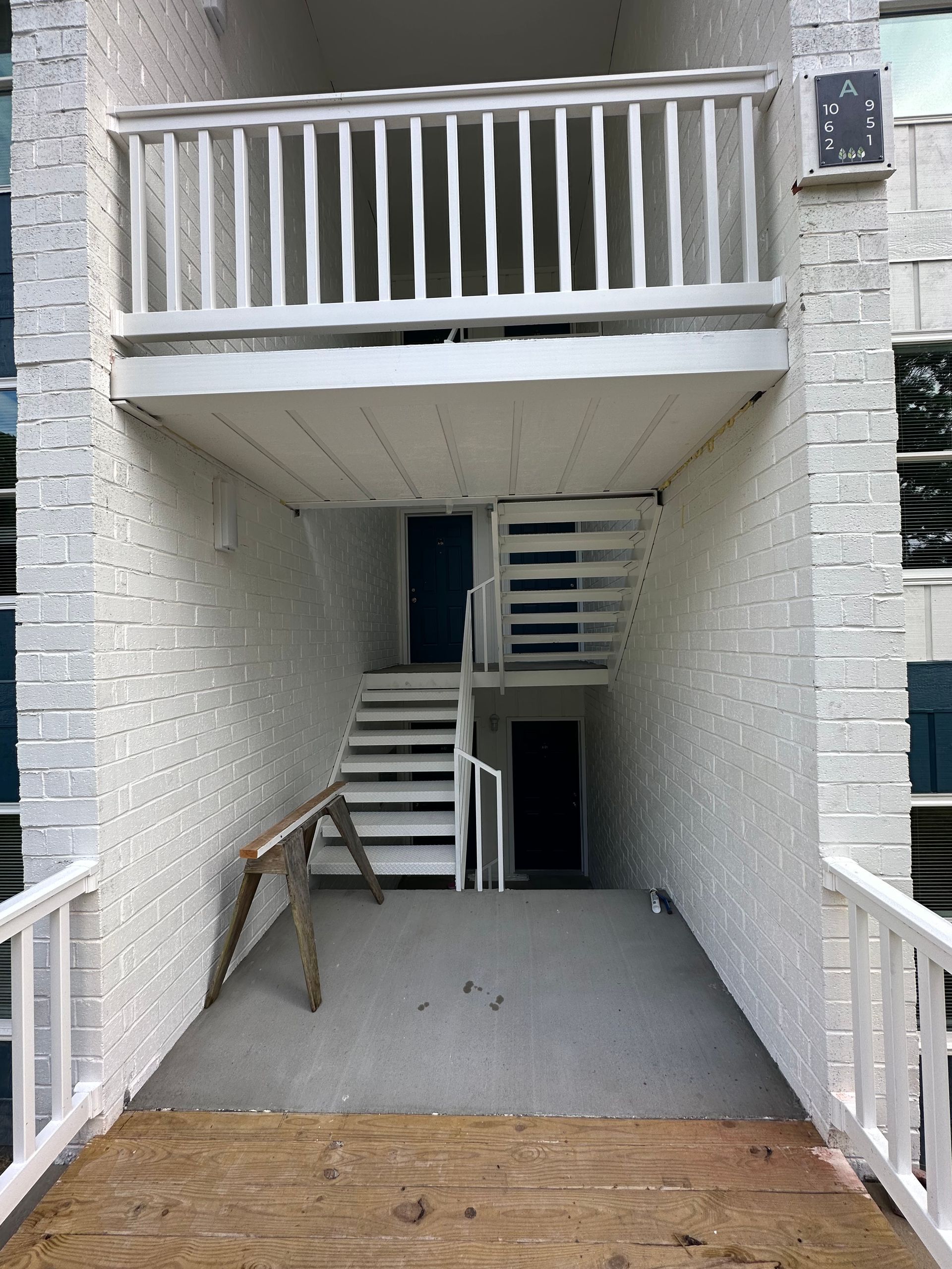 A white brick building with stairs and a balcony