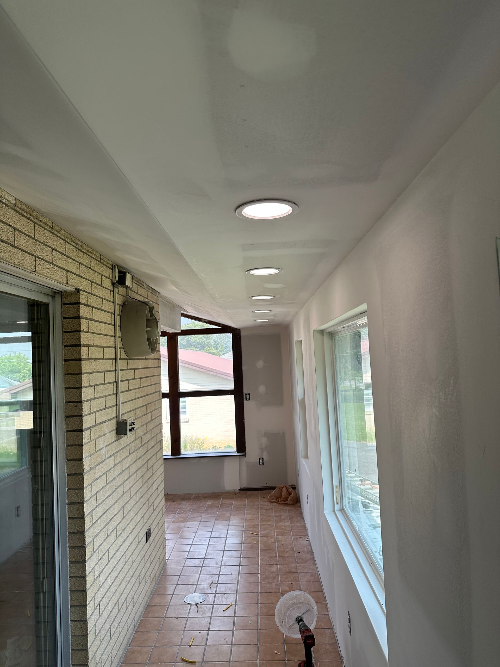A long hallway with a brick wall and tile floor.
