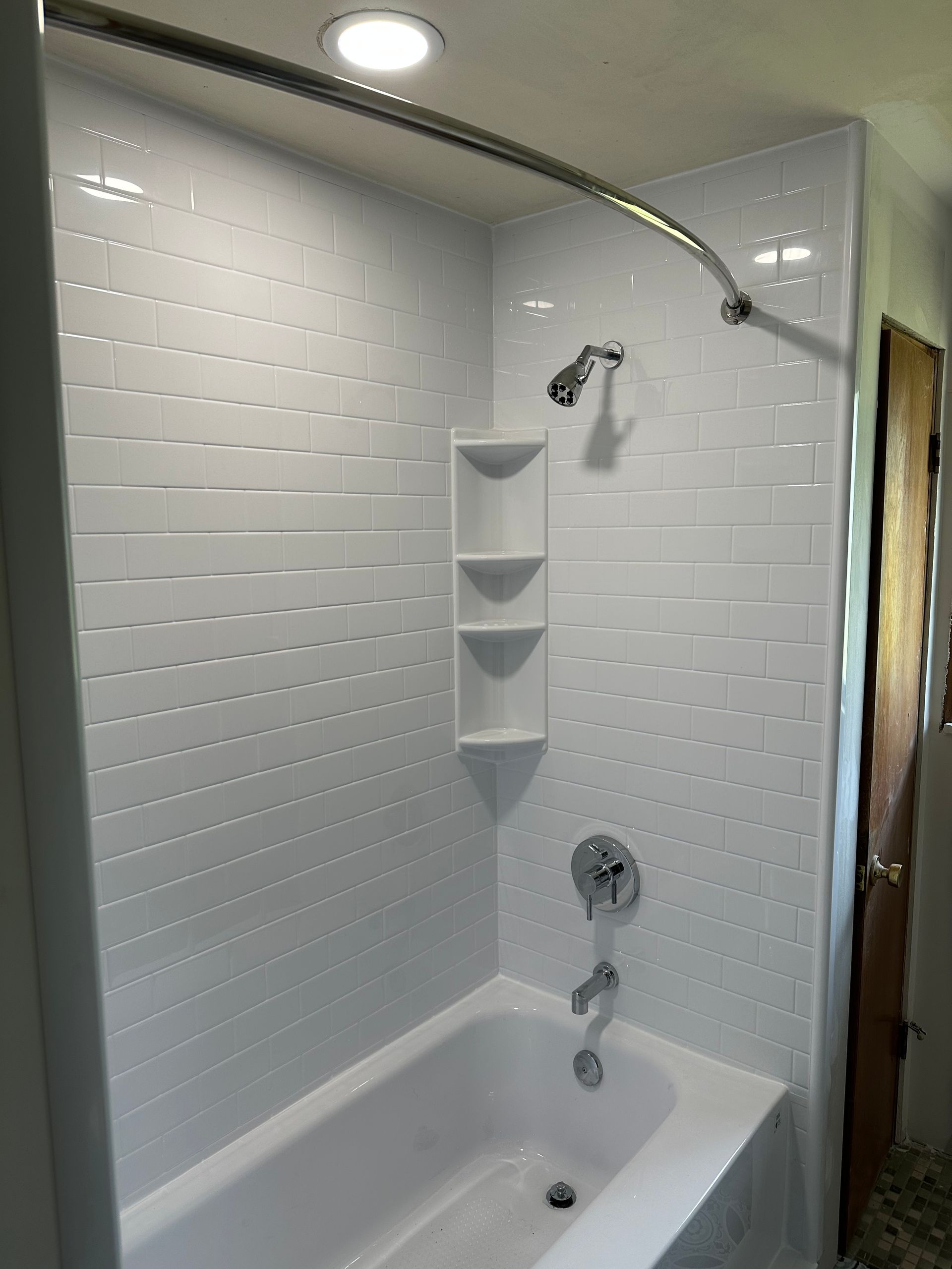 There is a bathtub in the shower with a shower head.