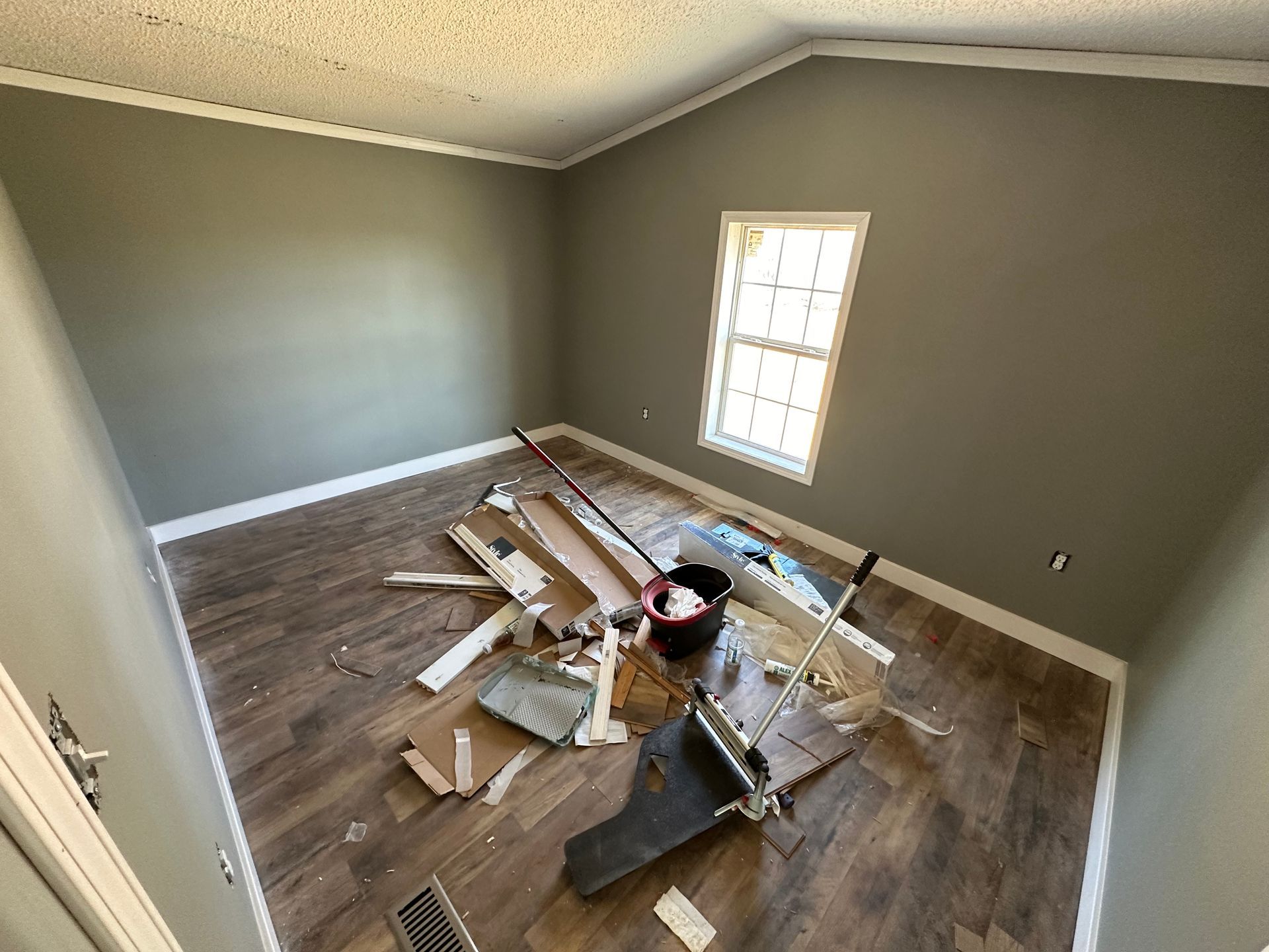 A room with a lot of junk on the floor and a window.