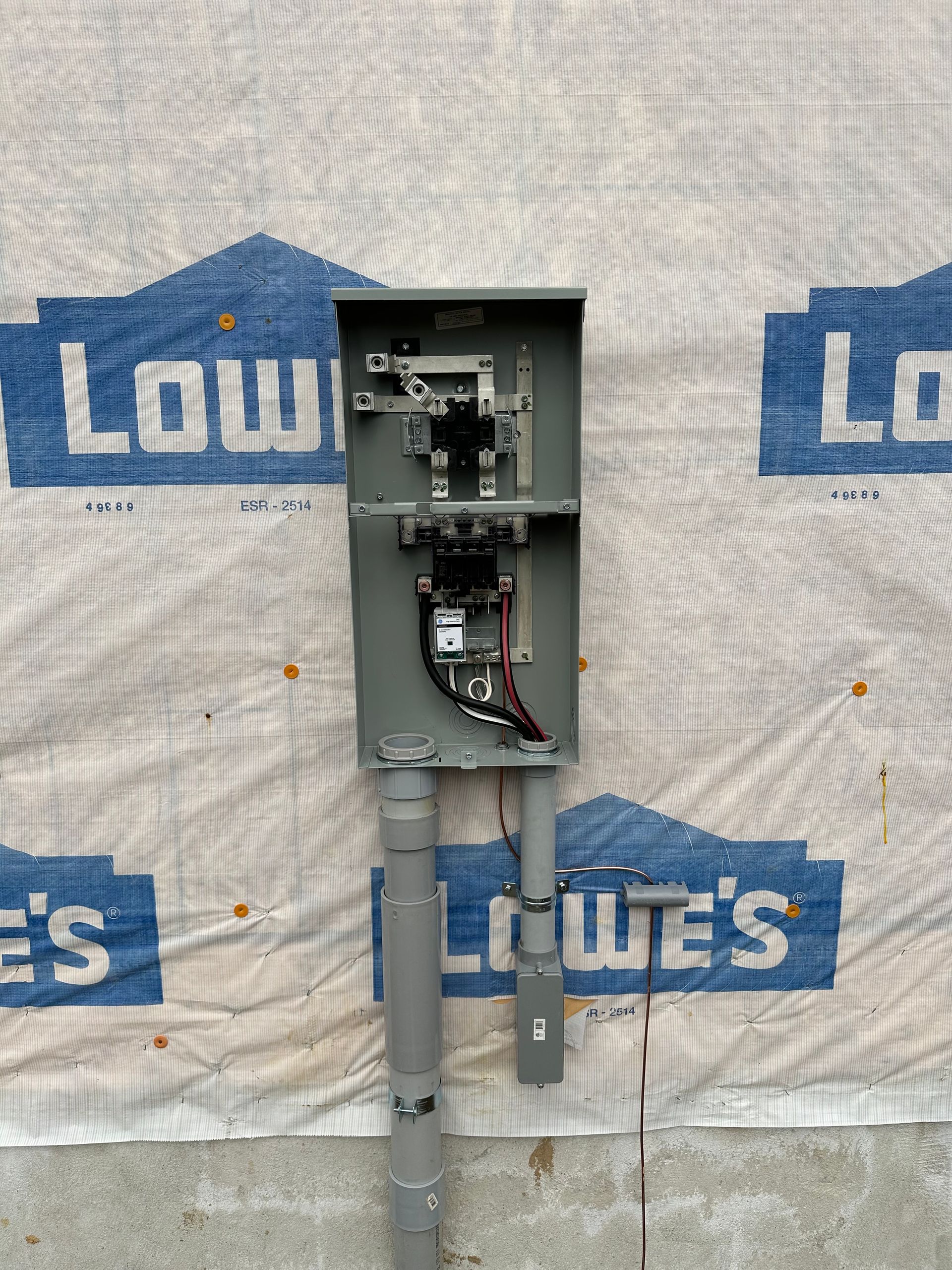 A lowe 's electrical box is attached to the side of a building.