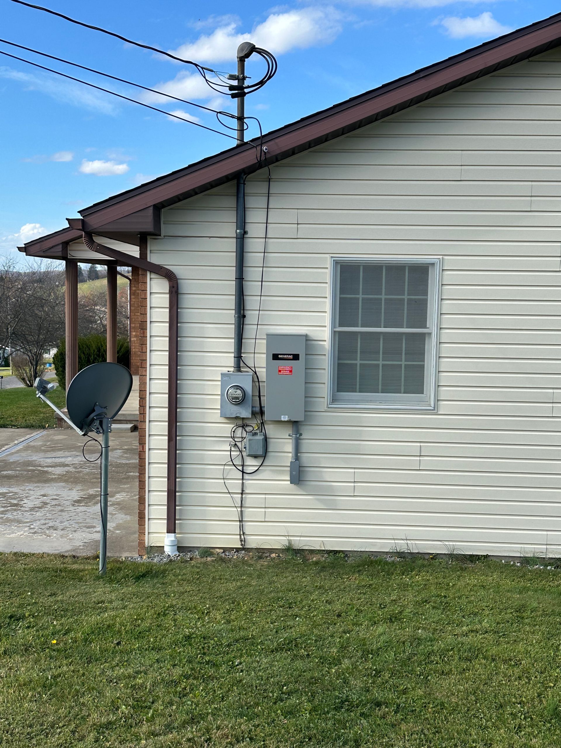 A white house with a window and a satellite dish on the side.
