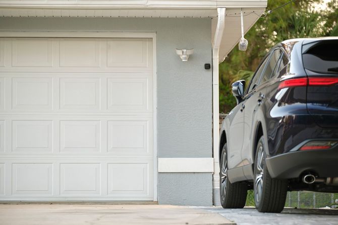 A car is parked in front of a garage door.