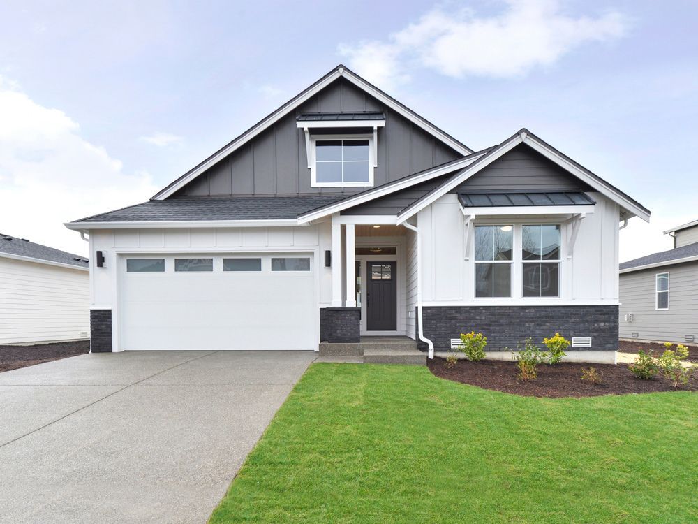 A white house with a black roof and a white garage door.