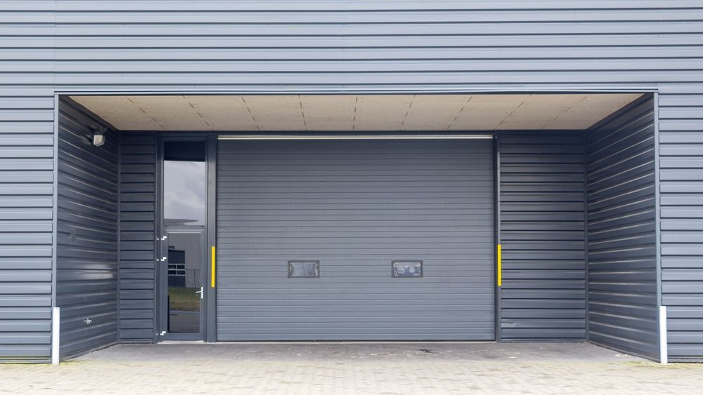 A gray garage door with a sliding door and a doorway.