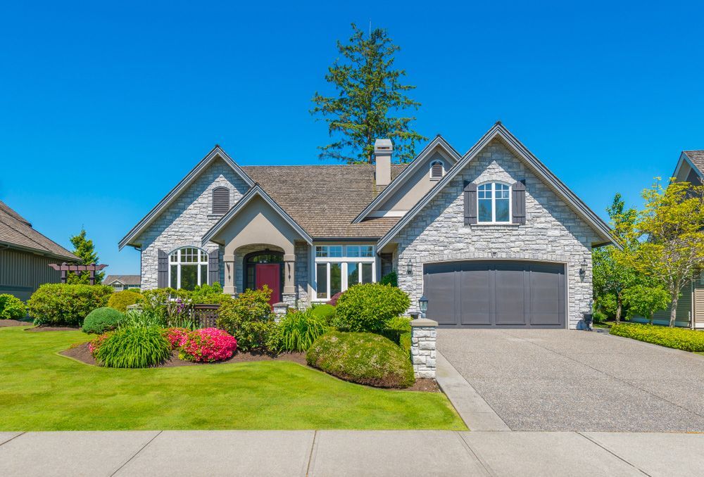 A large house with a large driveway and a lush green lawn.