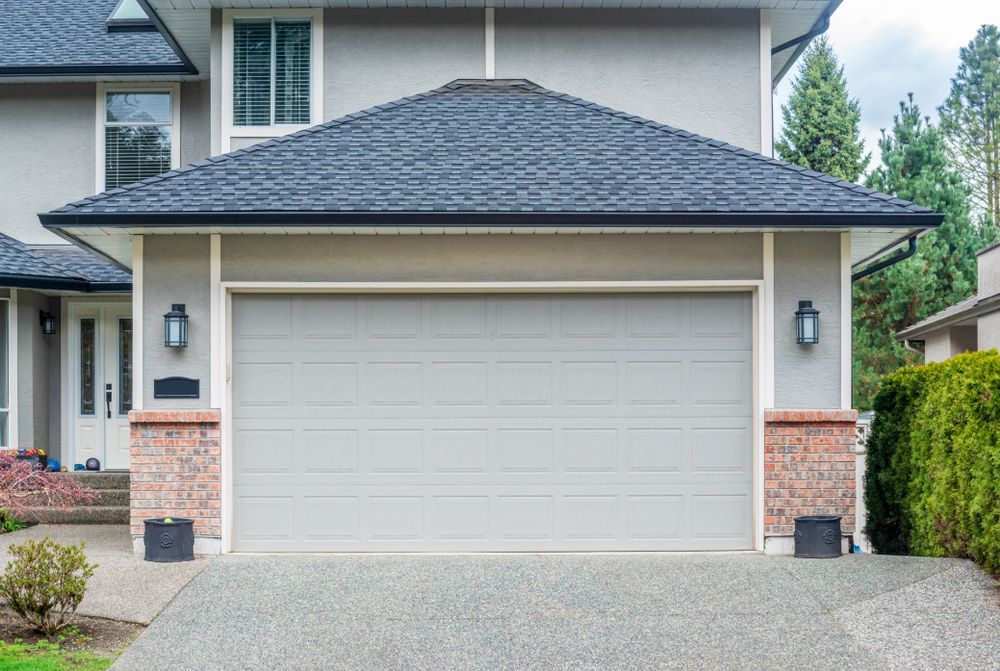 A large house with a gray garage door and a black roof.