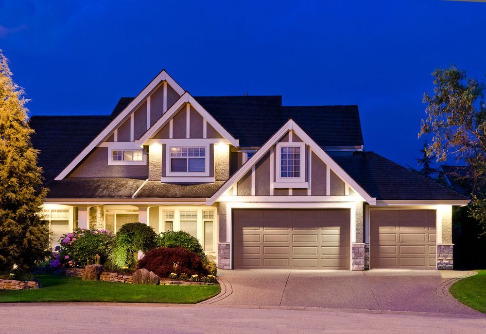 A house with two garage doors is lit up at night