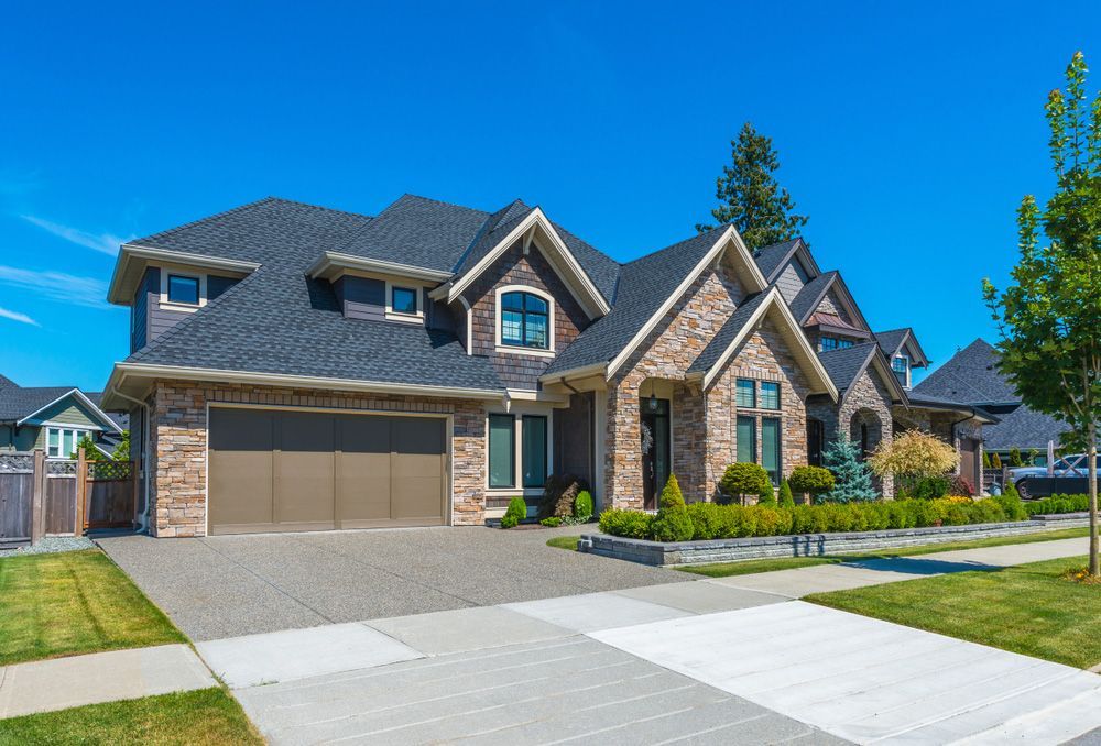 A large brick house with a garage and a driveway in a residential neighborhood.