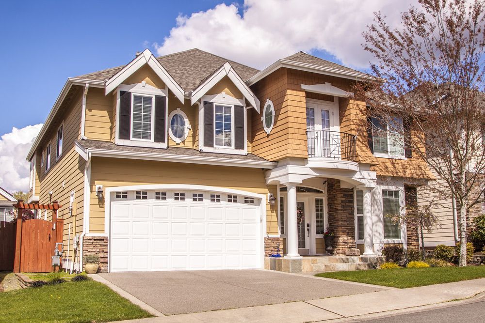 A large house with a white garage door in a residential neighborhood.