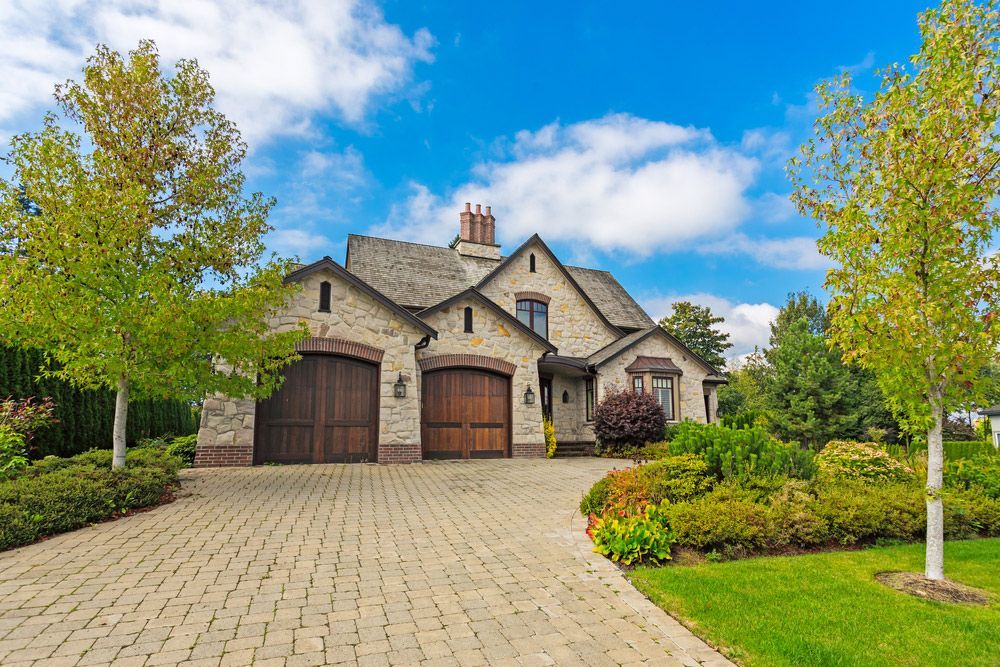 A large house with two garages and a brick driveway.