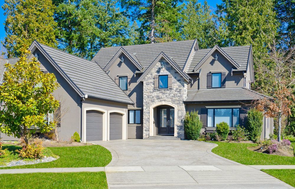 A large house with a gray roof is sitting on top of a lush green lawn.