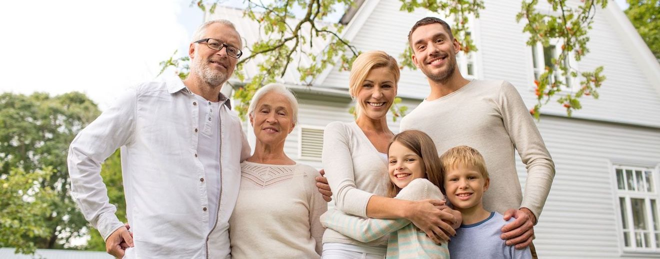 A large family is posing for a picture in front of a white house.