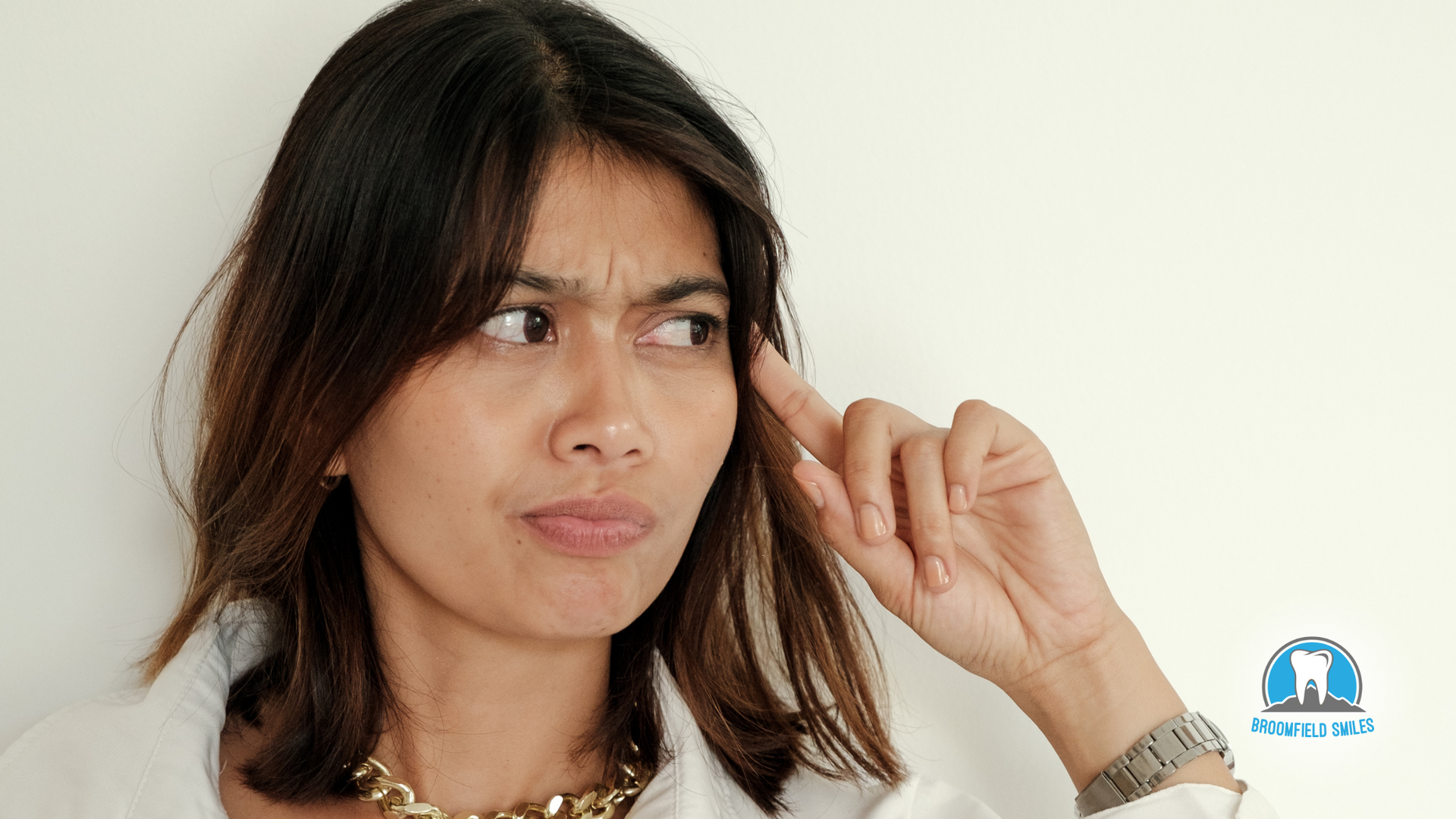 A woman is holding her hand to her ear and making a funny face.