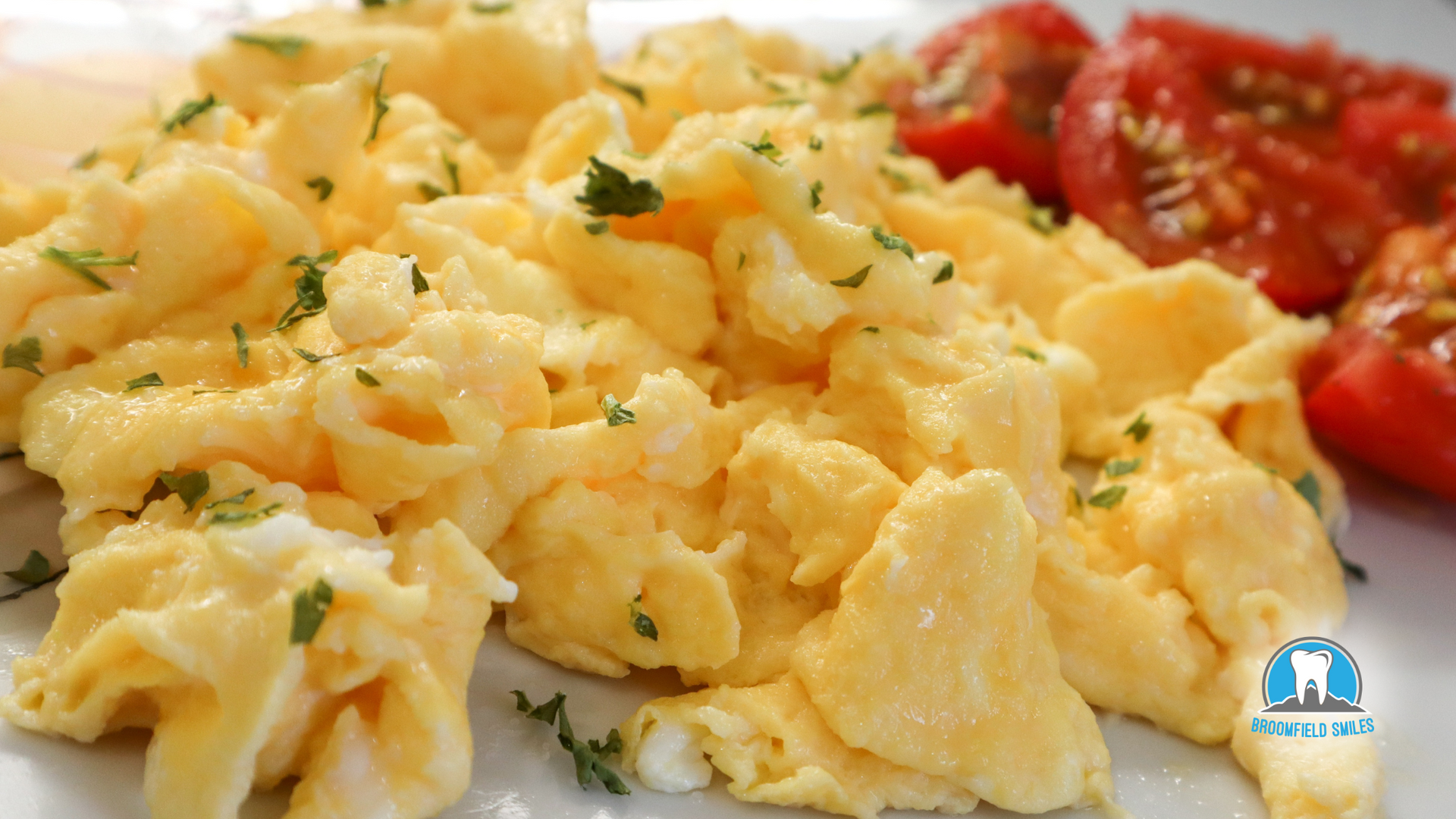 A plate of scrambled eggs and tomatoes on a table.