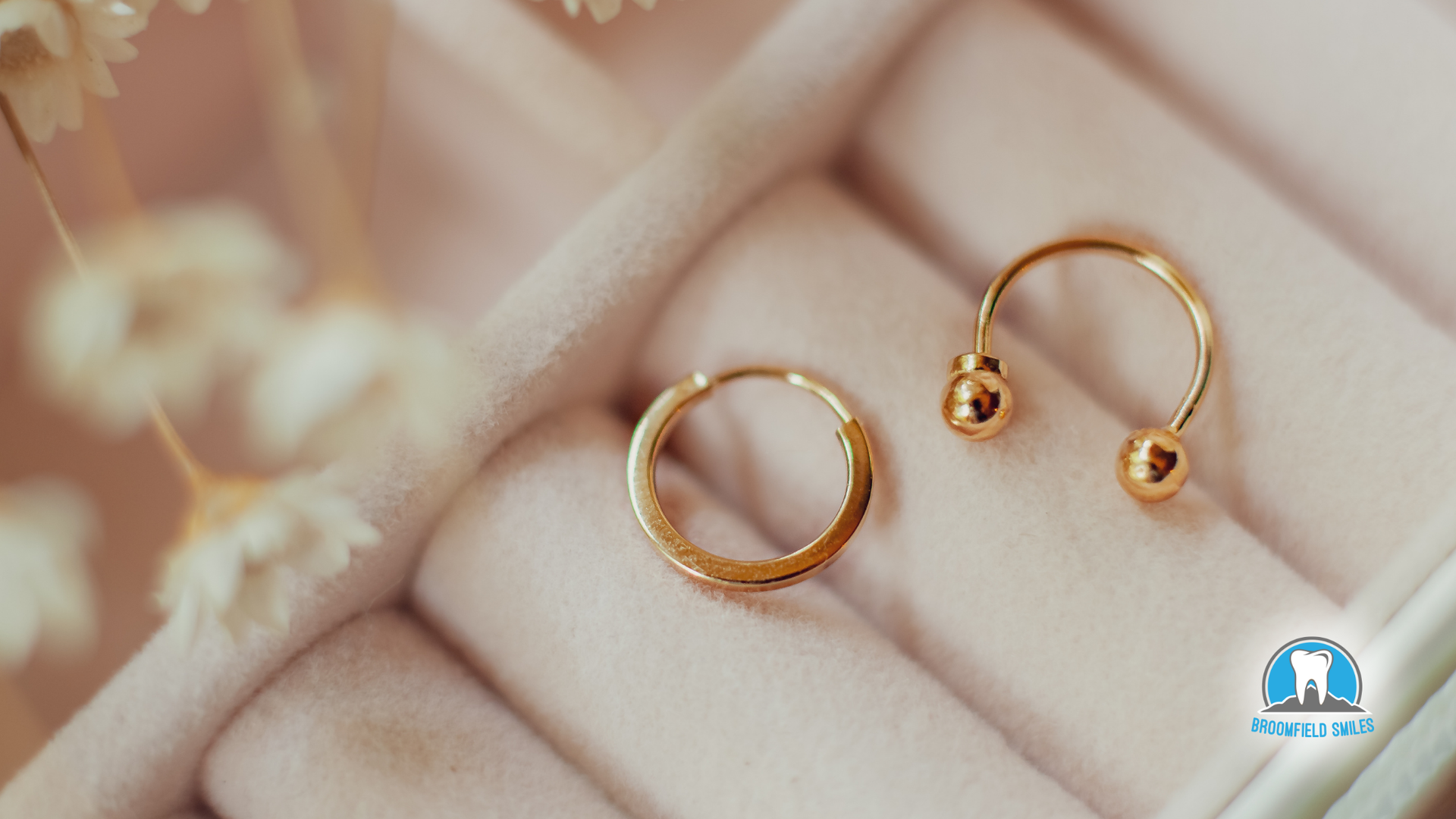 A pair of gold hoop earrings are sitting on a pink ring.