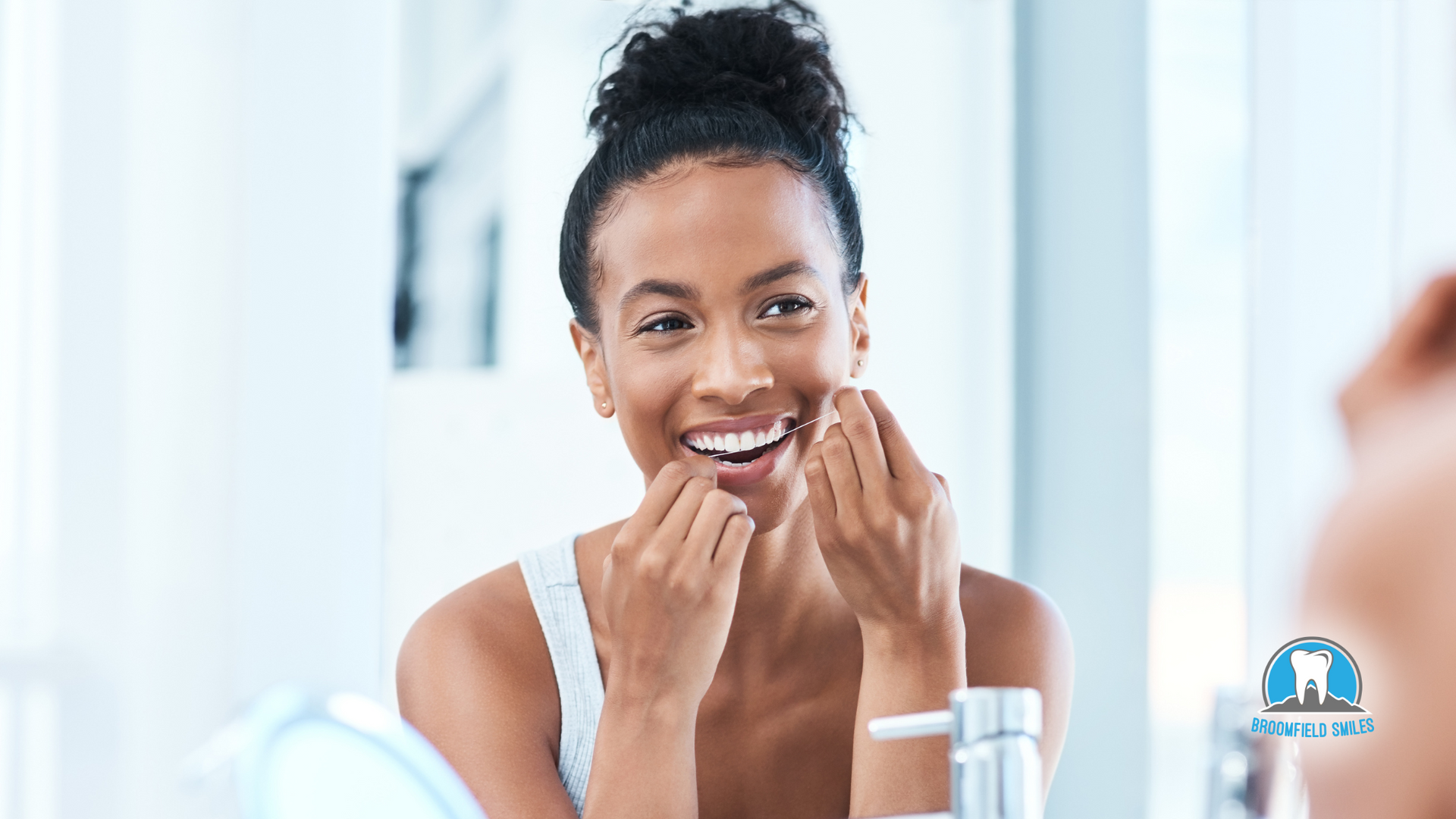 A woman is flossing her teeth in front of a mirror.