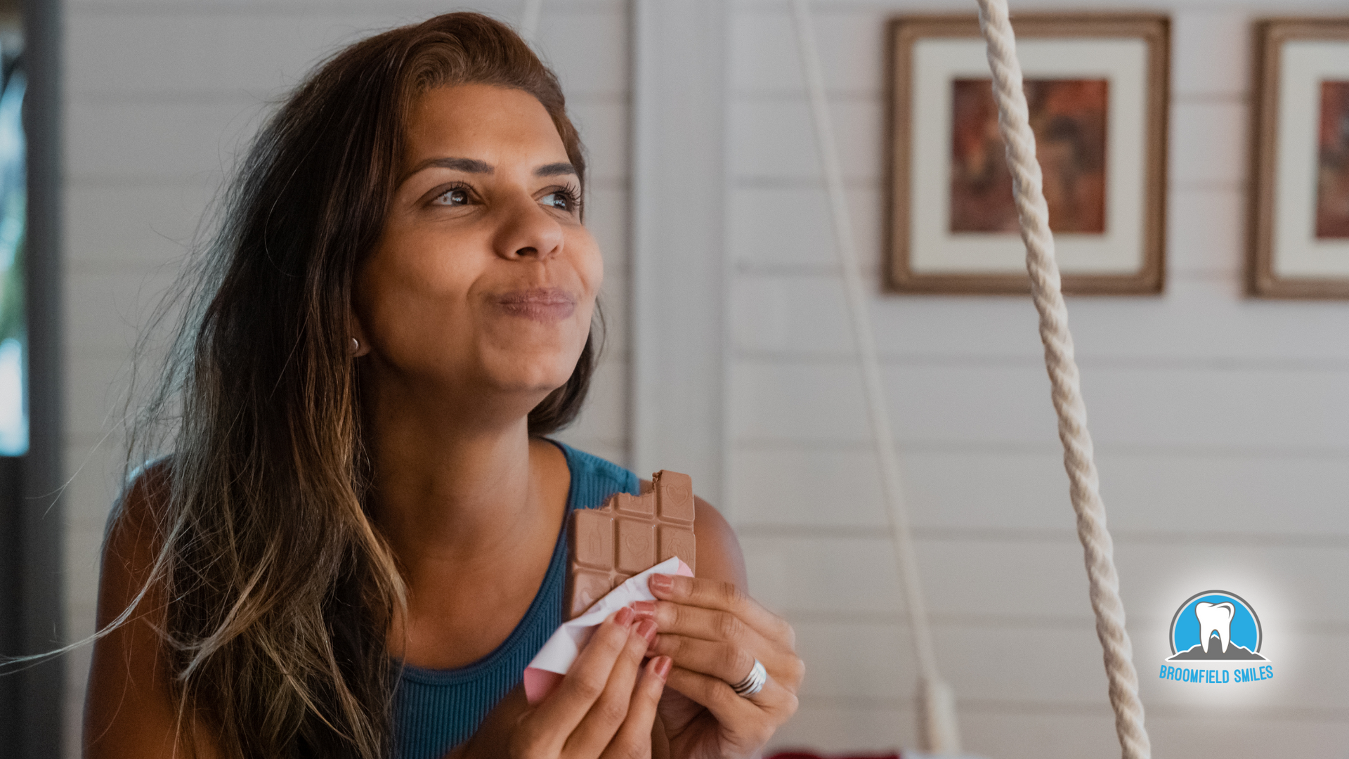 A woman is eating a chocolate bar on a swing.