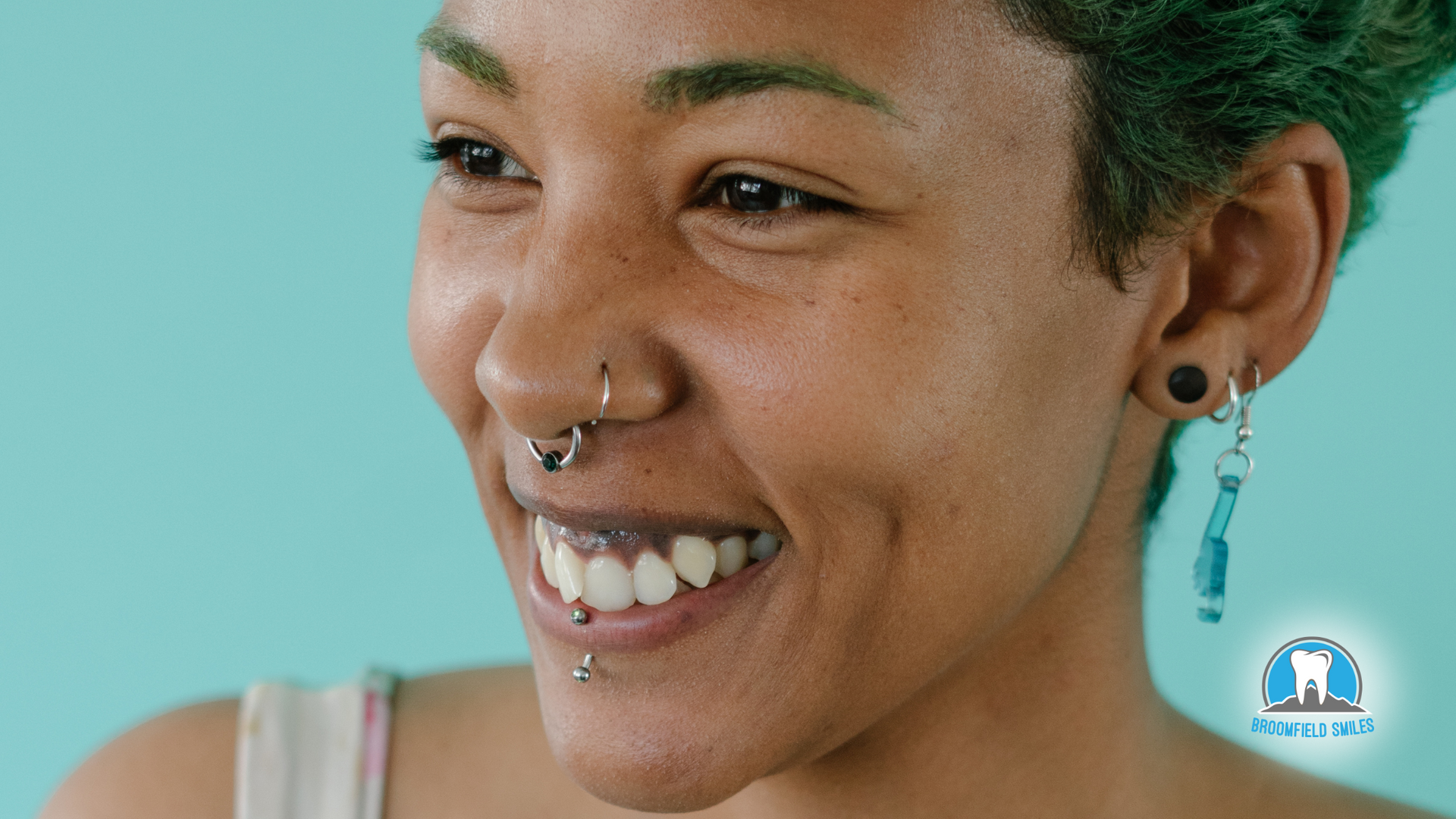 A woman with a nose ring and earrings is smiling.