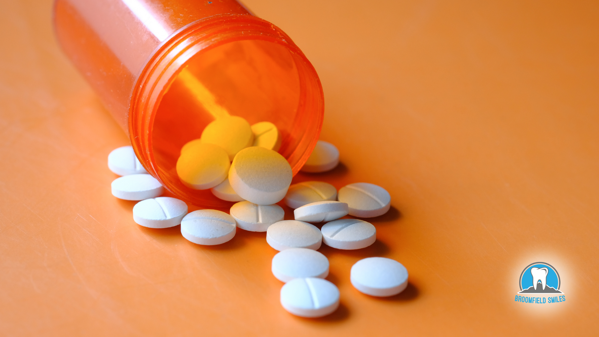 A bottle of pills is spilling out onto a table