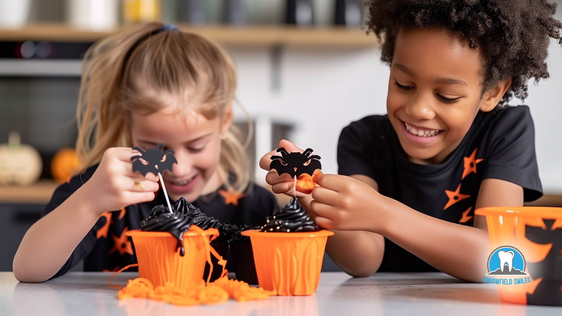 Two children decorating Halloween cupcakes with spider toppers.