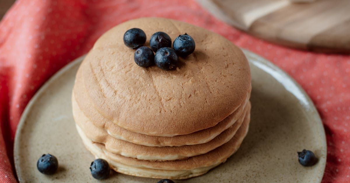 A stack of pancakes with blueberries on top on a plate.