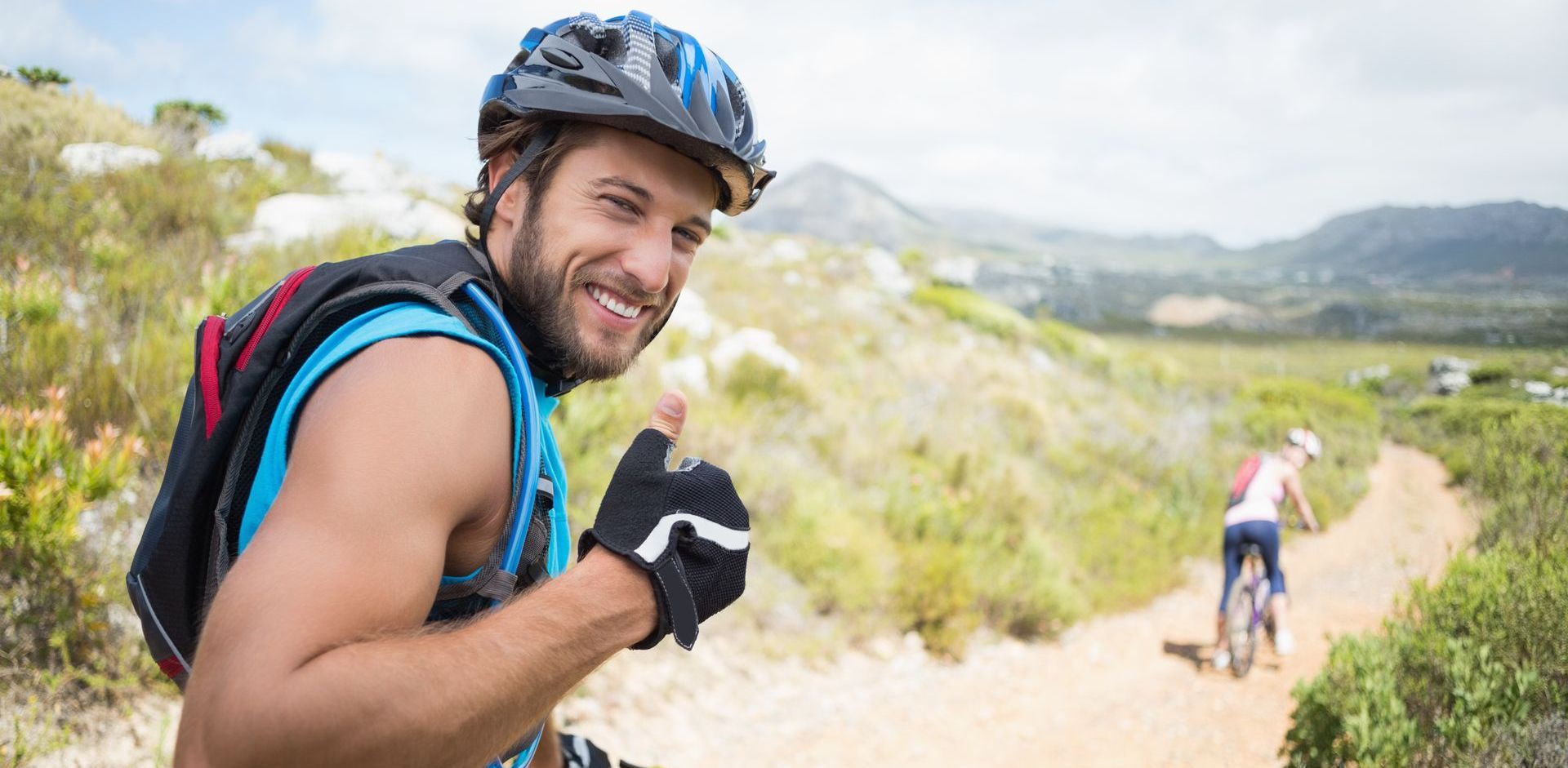 Man is giving a thumbs up while riding a bike on a trail after visiting Stem Cells Philadelphia for aesthetics and  regenerative medicine treatments.