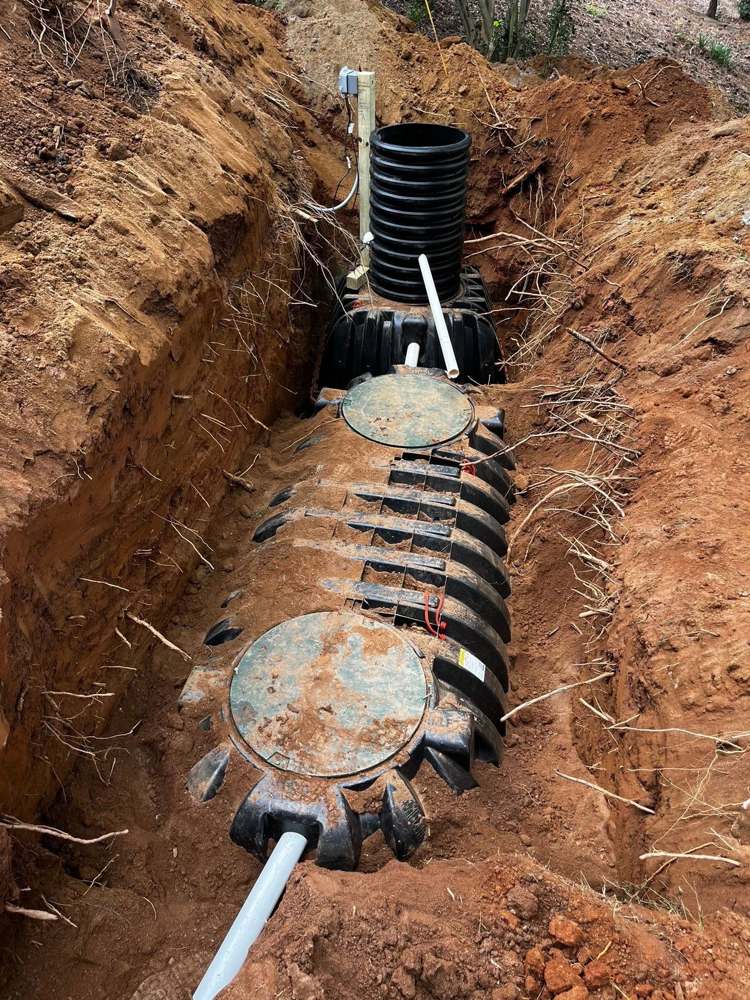 Septic tank system installation in a trench, including tank and vertical access tube.
