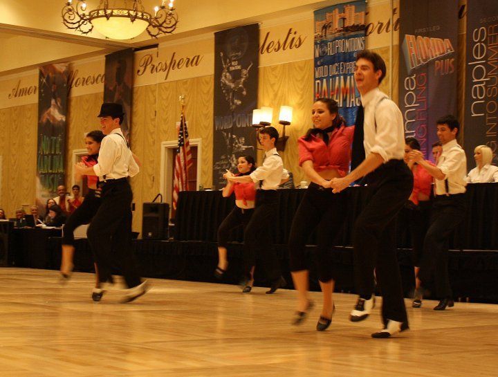 A group of people are dancing in front of a wall that says prospera