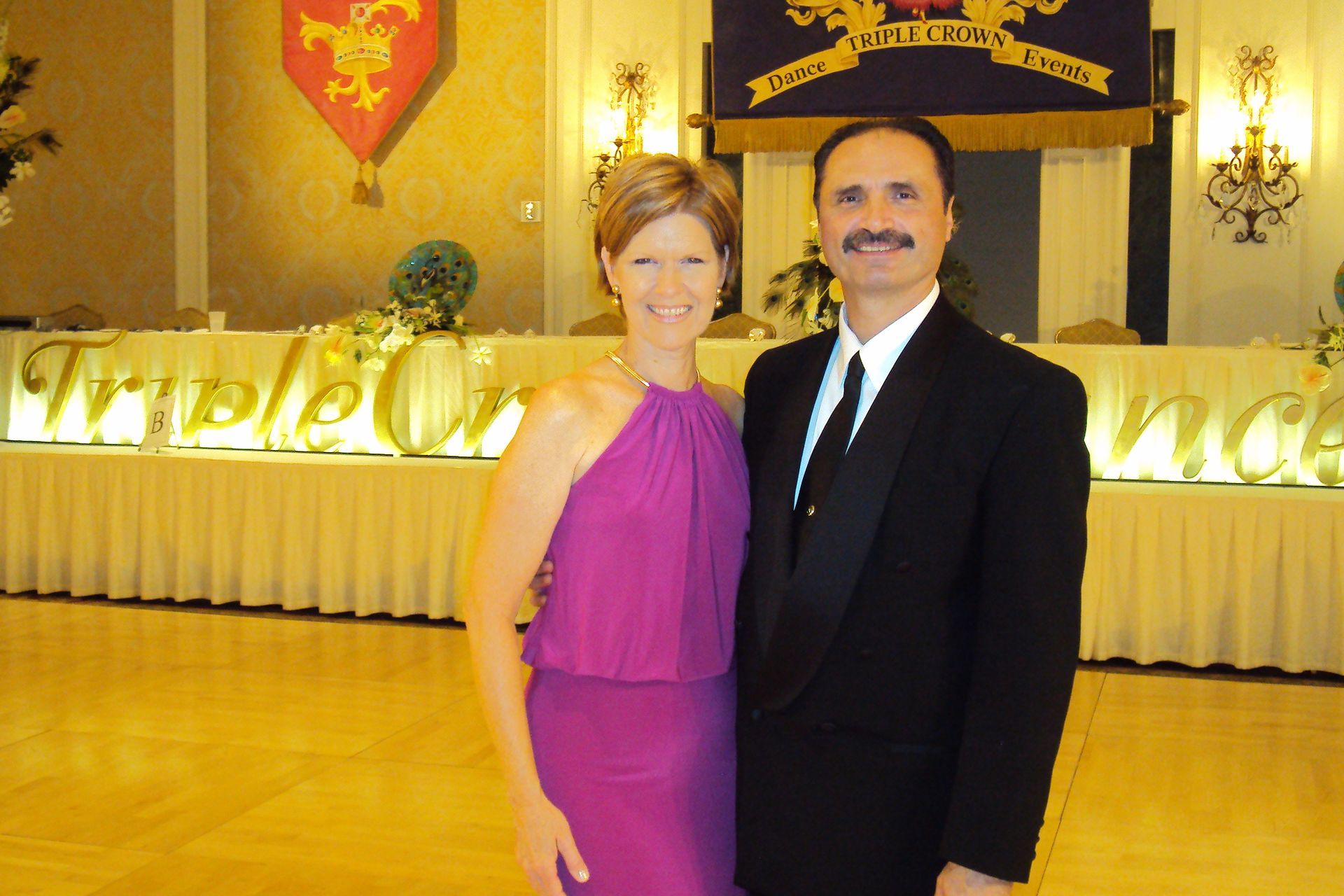 A man and a woman are posing for a picture in front of a table that says 
