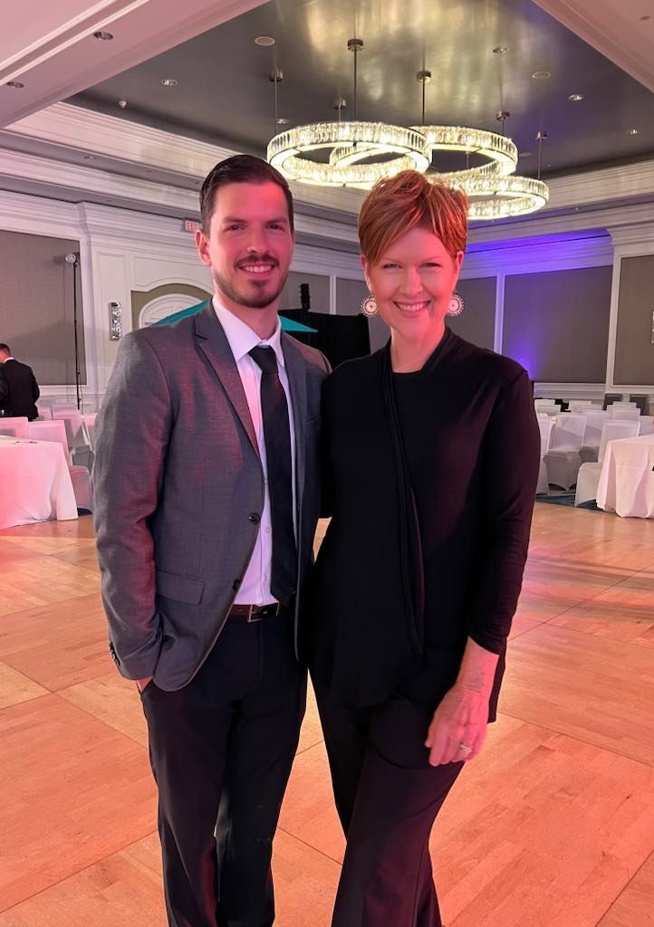 A man and a woman are posing for a picture in a ballroom.