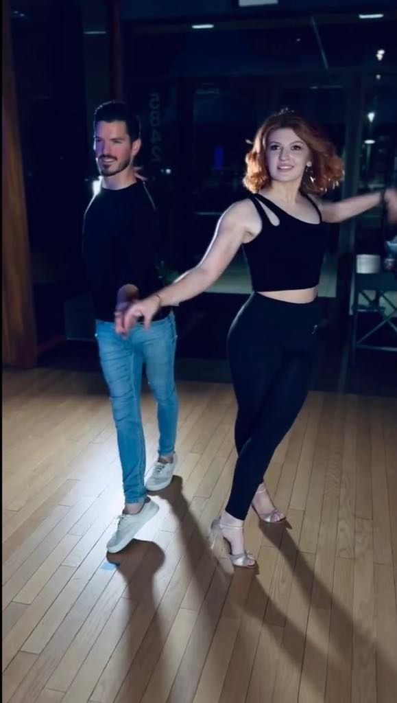 A man and a woman are dancing on a wooden floor.